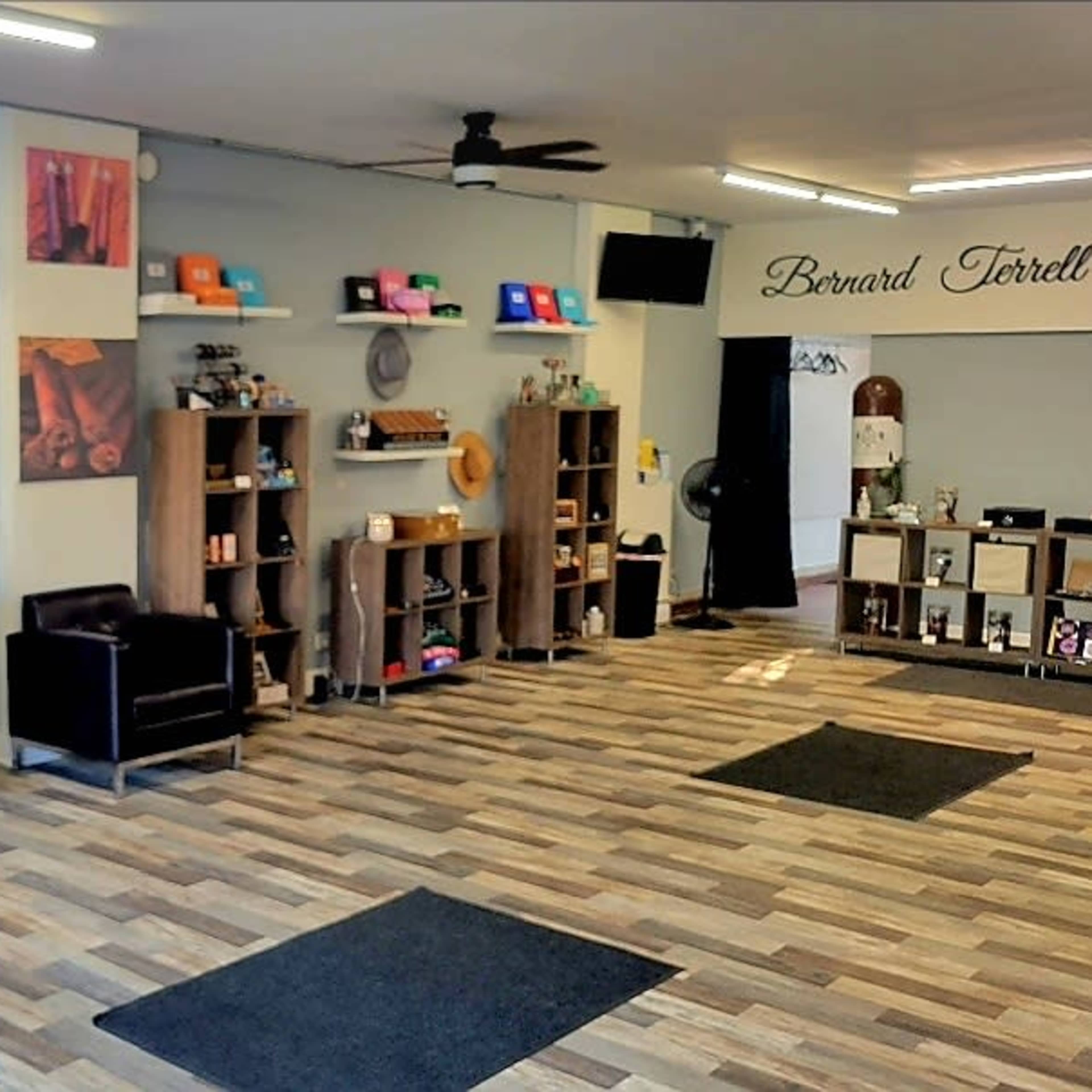 An interior retail space with shelves displaying various products, including clothing and accessories, arranged neatly along the walls, and a seating area in the corner.