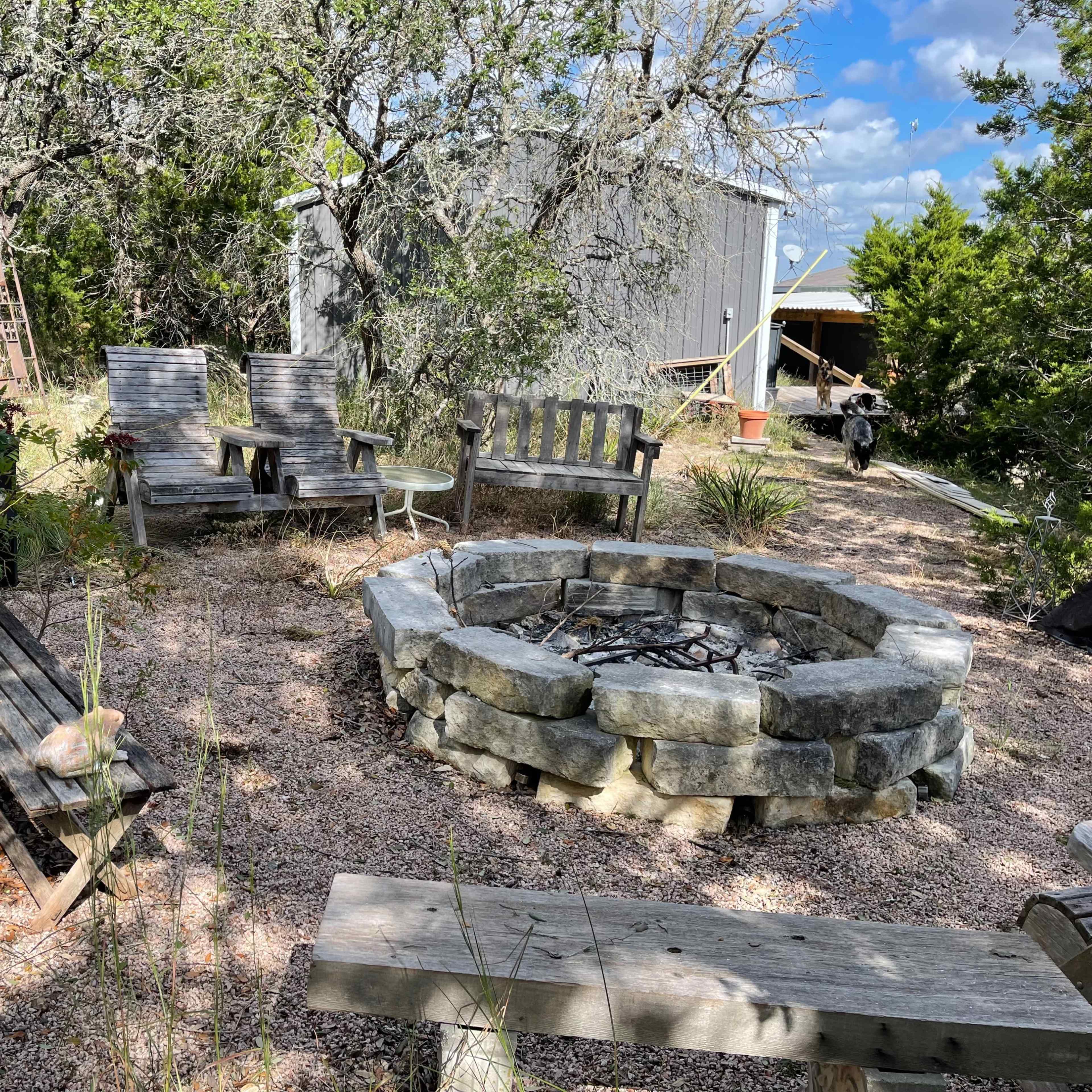 A fire pit surrounded by wooden seating and natural landscaping.