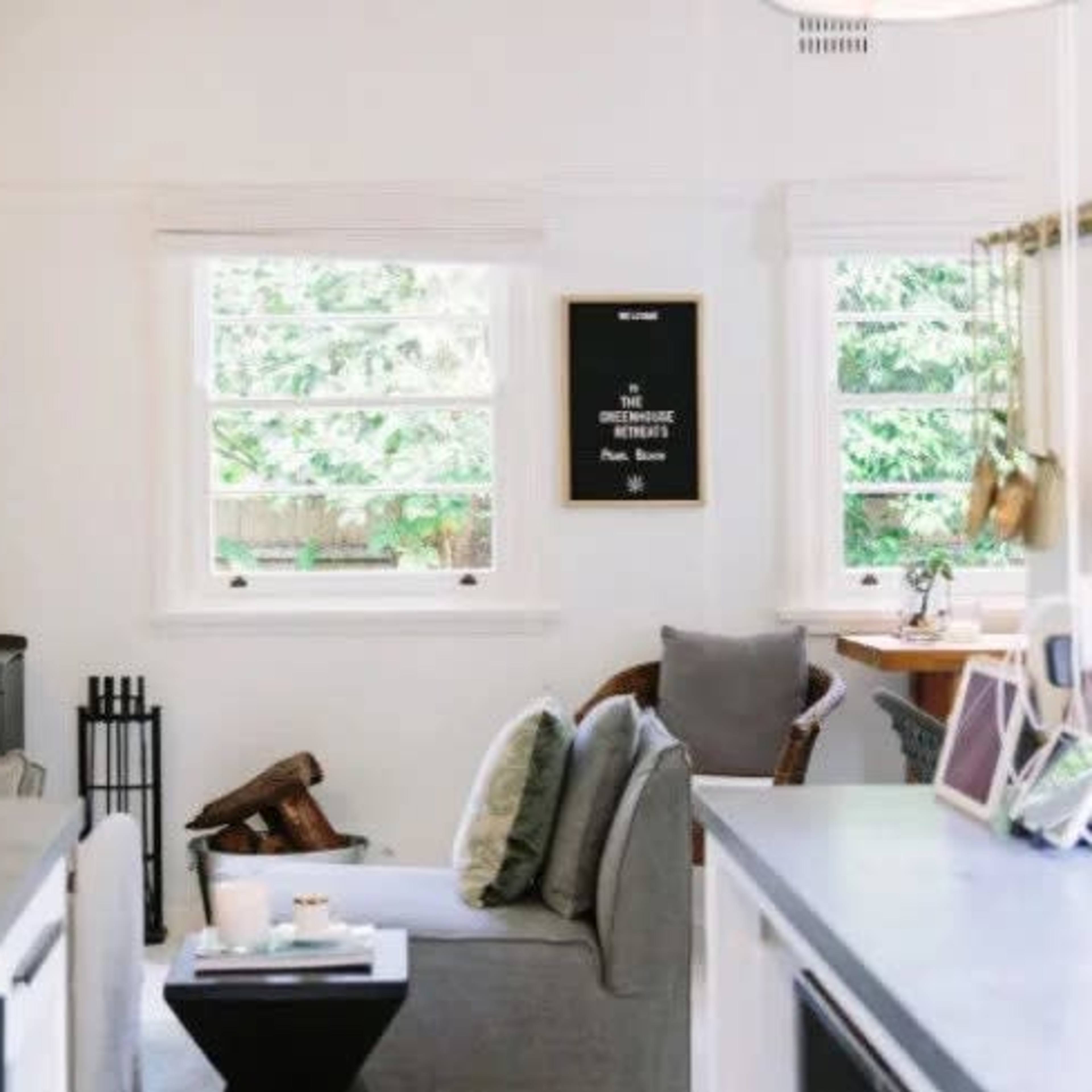 A cozy living space featuring a gray sofa, a small black side table, and a wood stove in front of a window with greenery outside.