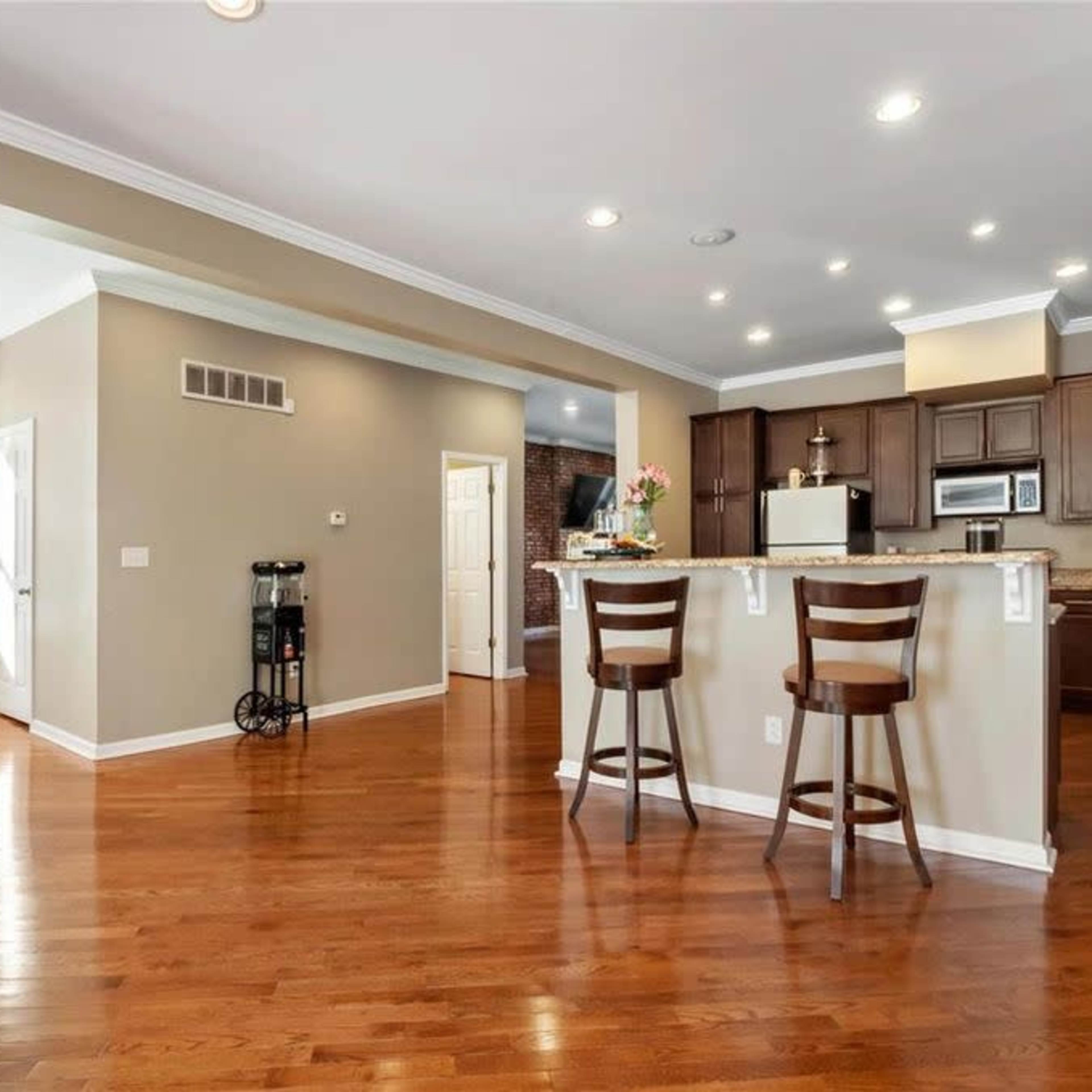 A spacious, open-concept kitchen and living area with hardwood flooring and dark wood cabinetry.