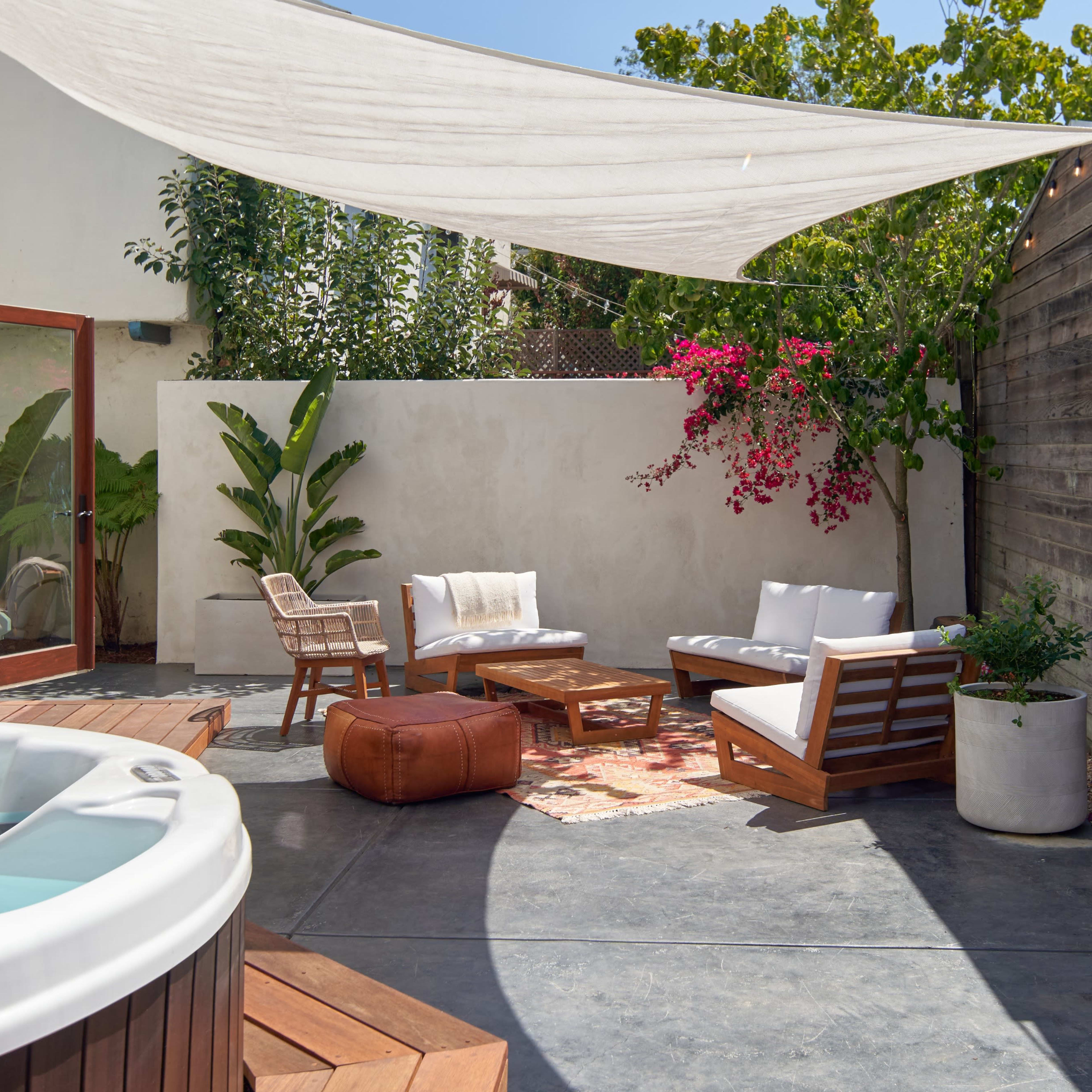 A private outdoor patio features a hot tub, comfortable seating, and decorative plants under a shaded canopy.