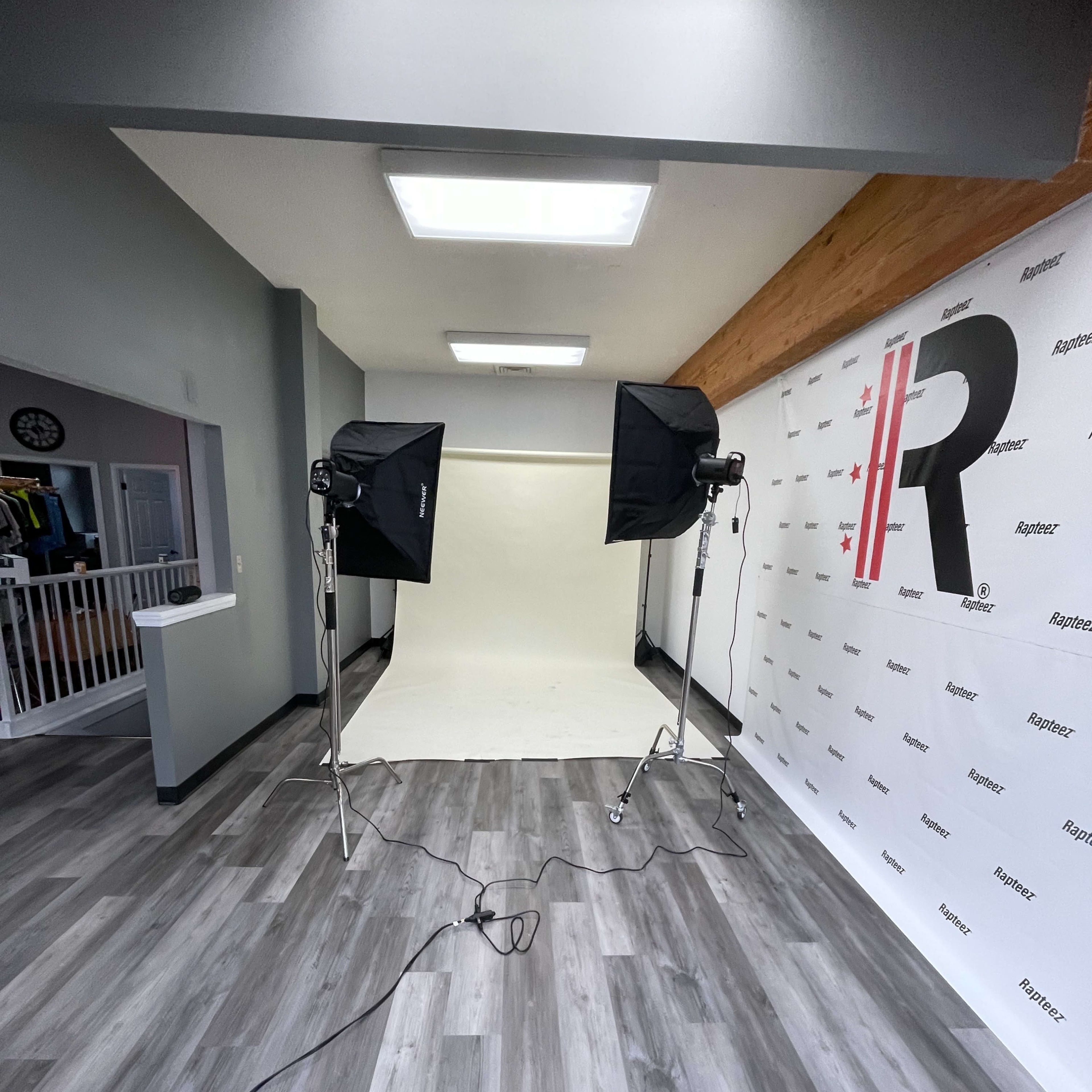A photography studio setup with a seamless background, two softbox lights, and a floor with wooden laminate.
