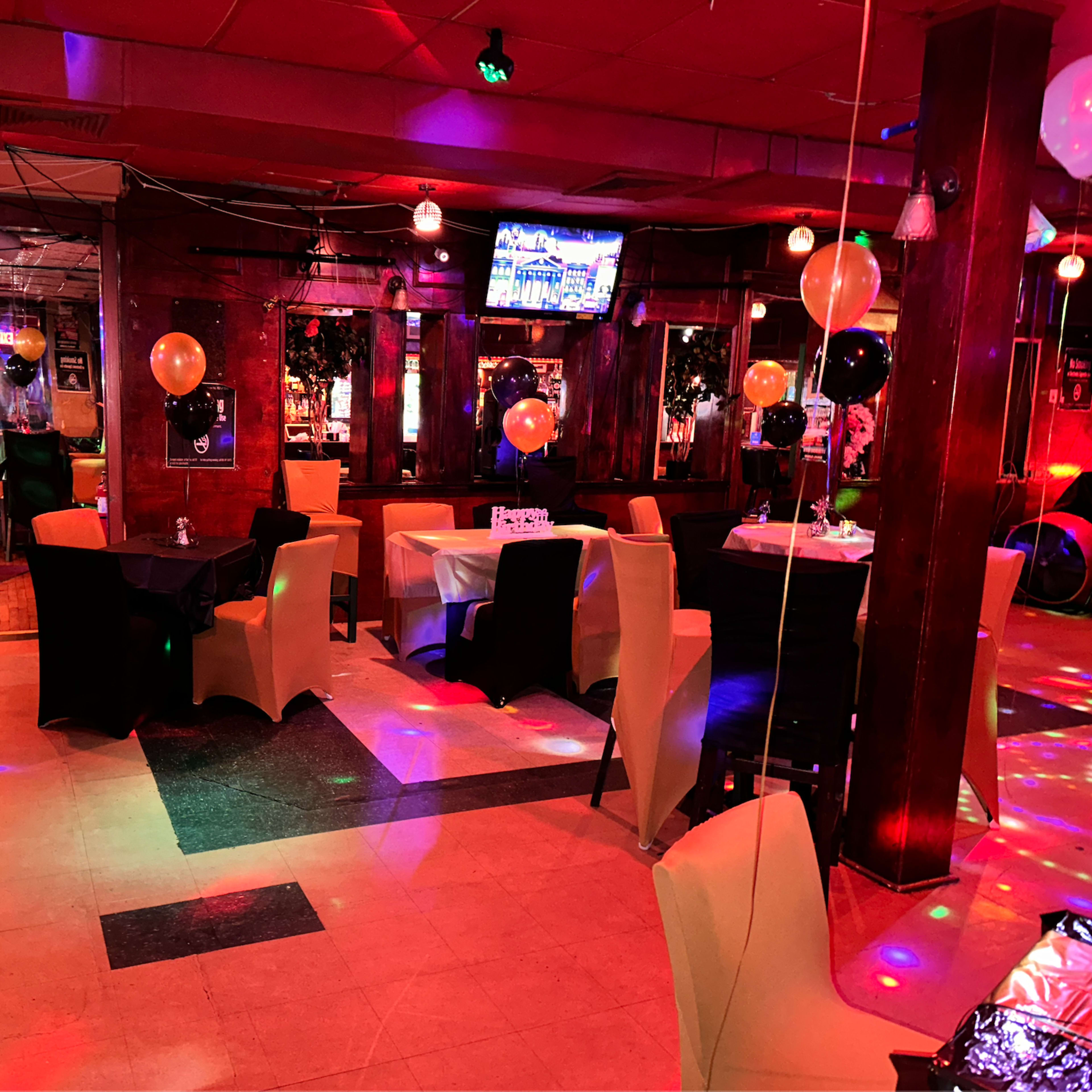 A decorated restaurant interior with tables, chairs, and colorful lighting effects.