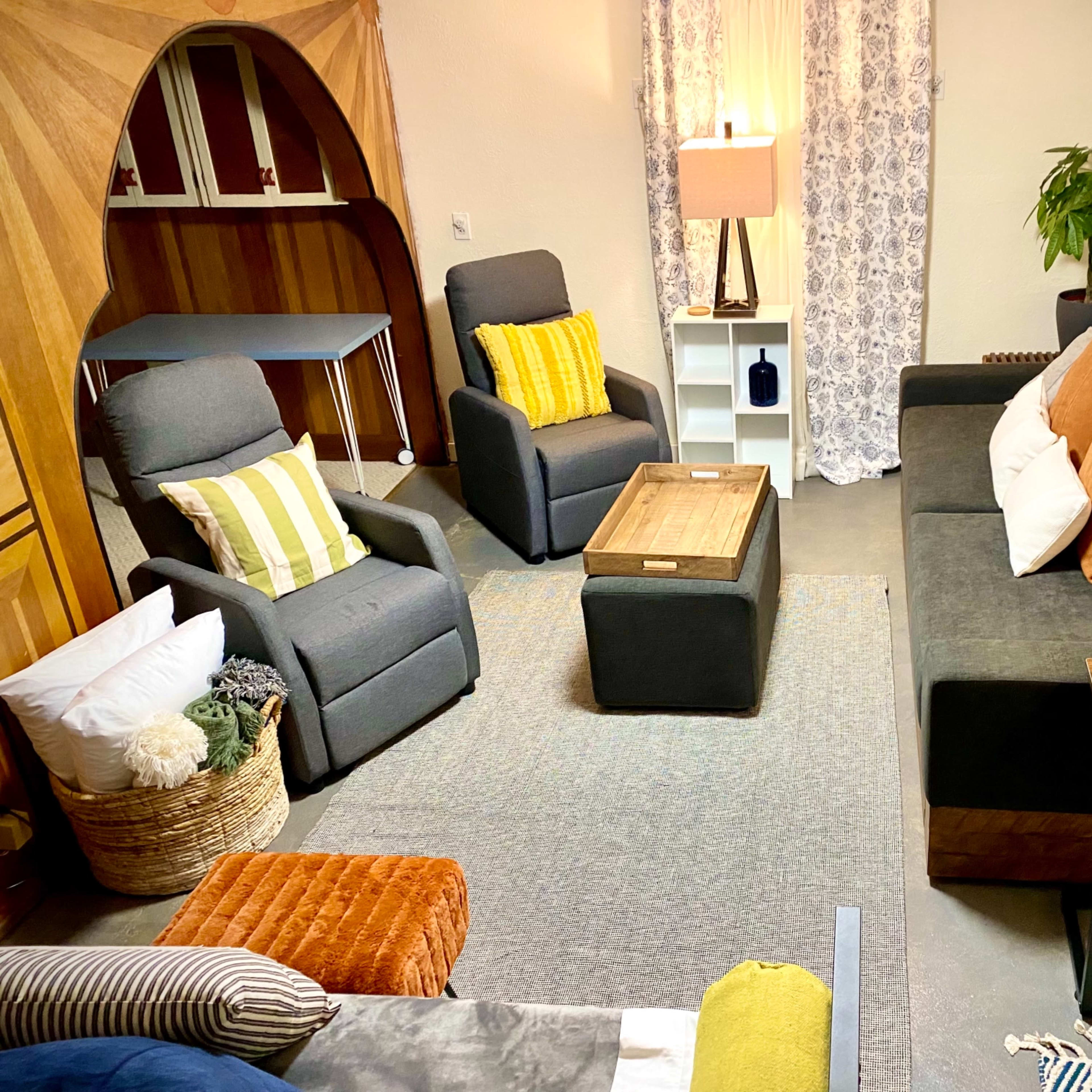 A cozy living room setup with multiple seating options, a coffee table, and decorative elements, illuminated by soft lighting.