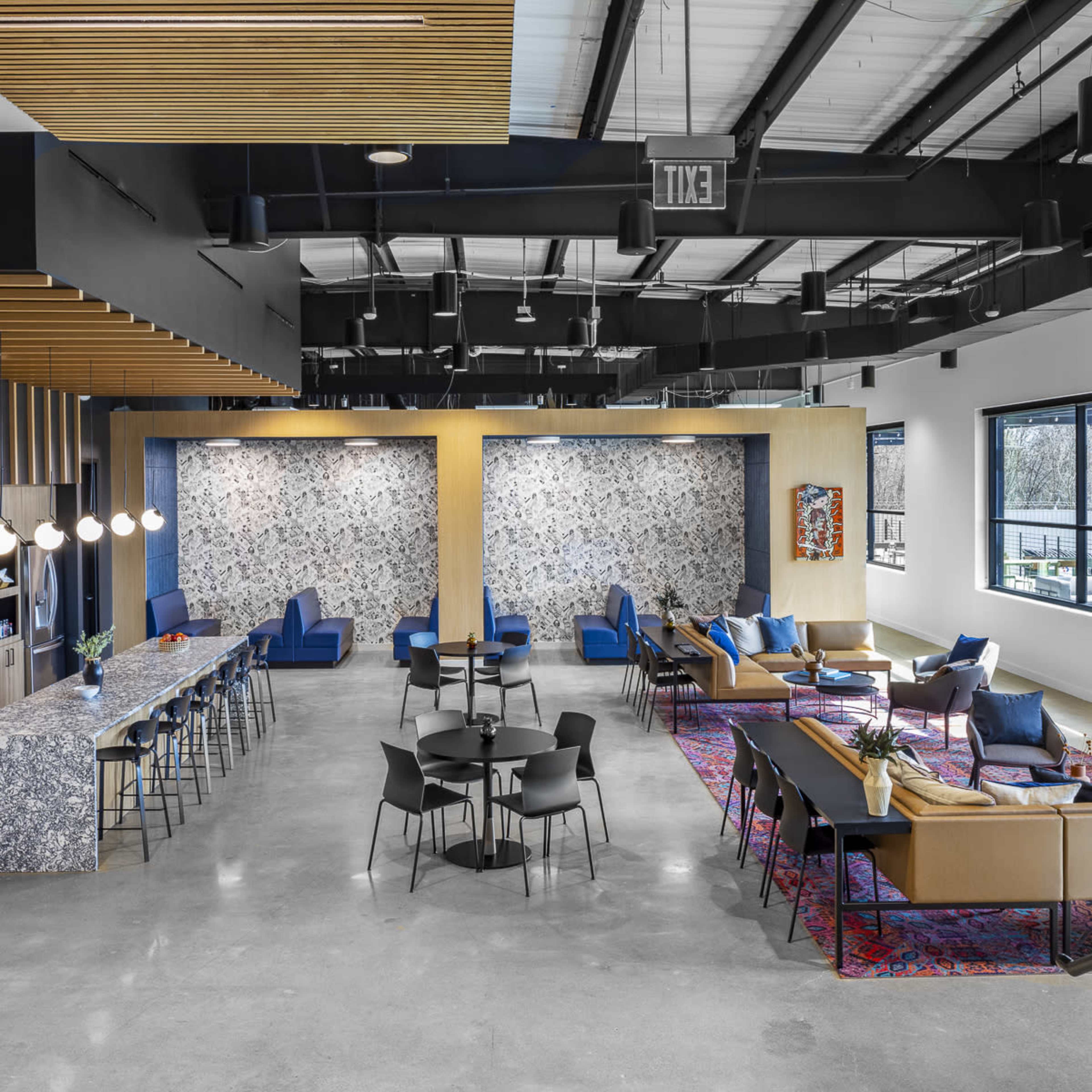 A modern open-concept lounge area featuring a long bar, various seating arrangements, and decorative wall art.