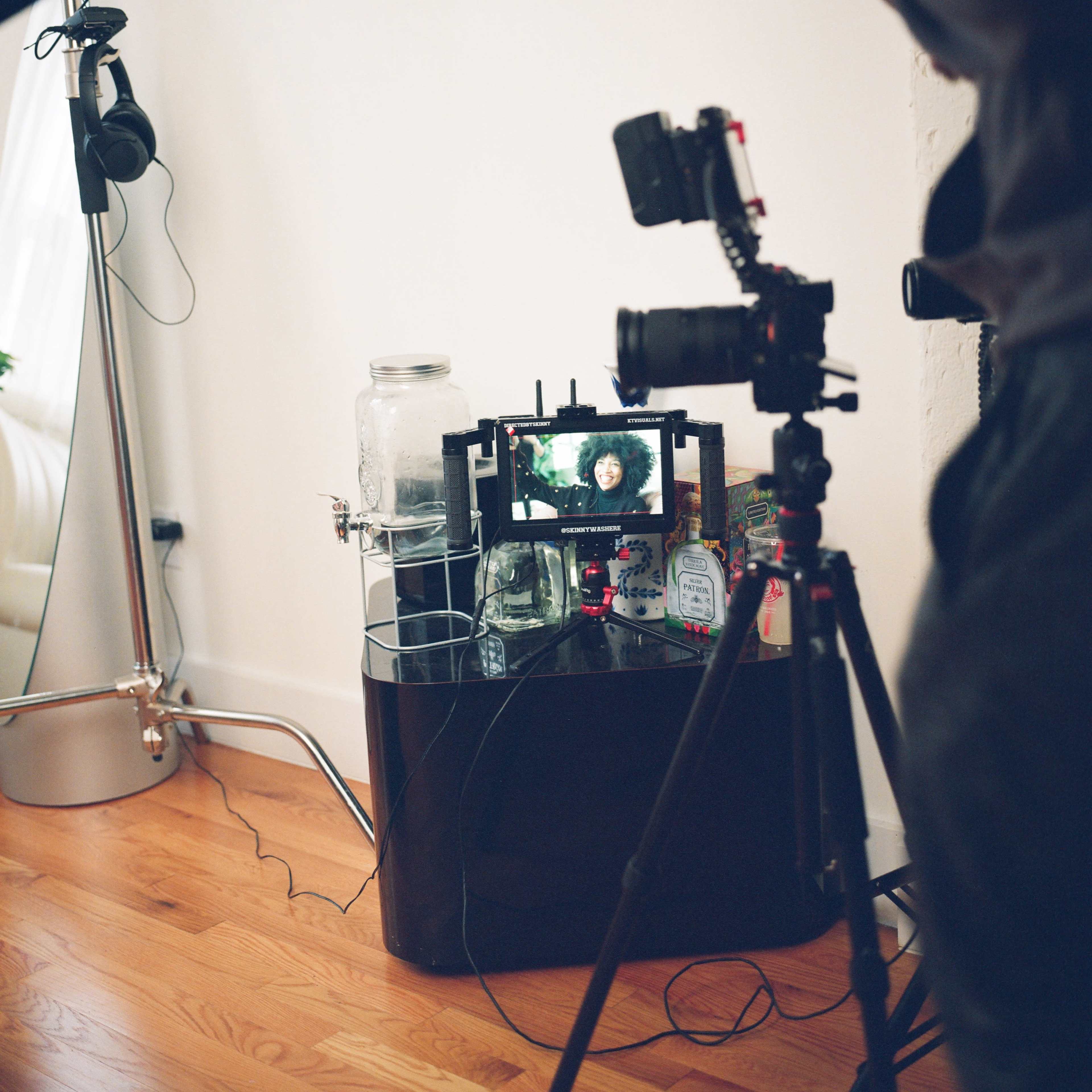 A black table holds various glass jars and a camera setup facing a small screen displaying a person's image.