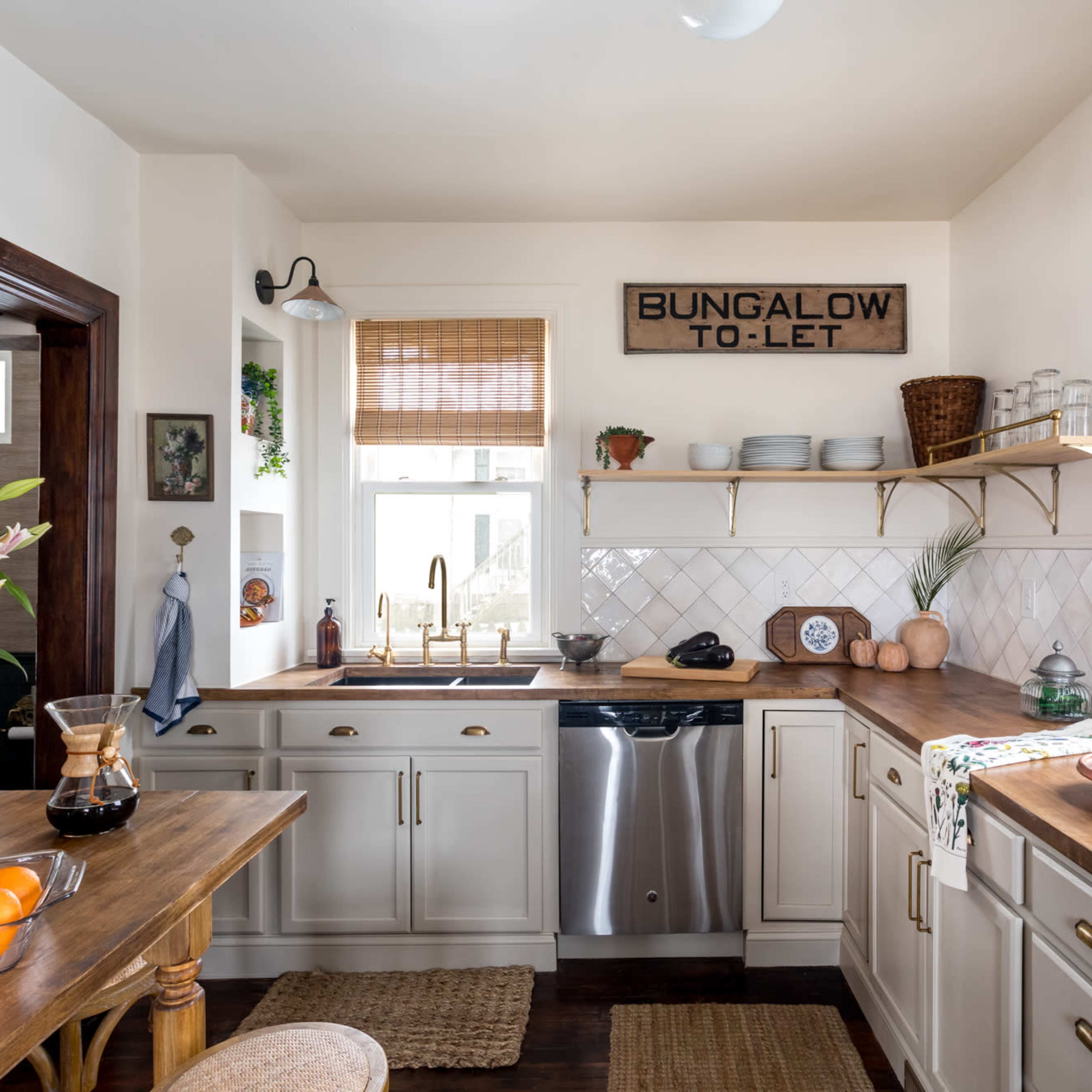 A kitchen features a mix of white cabinets, wooden countertops, and open shelving with decorative items.