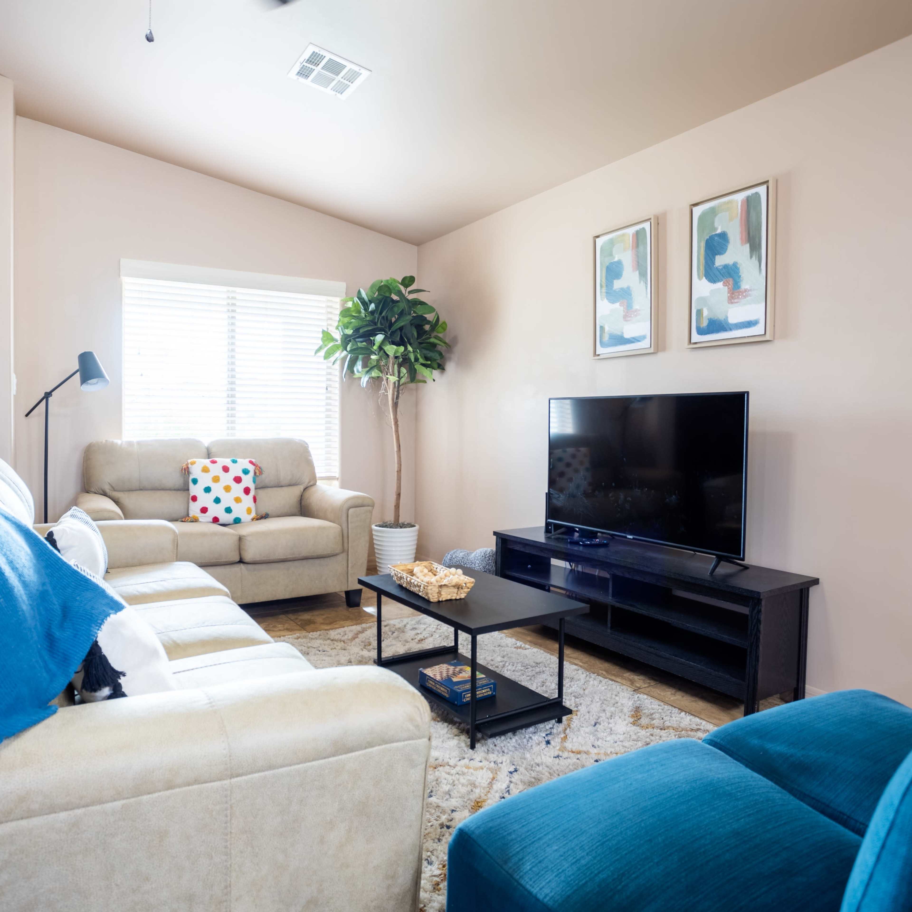 A living room with two sofas, a coffee table, a television stand, and decorative artwork on the walls.