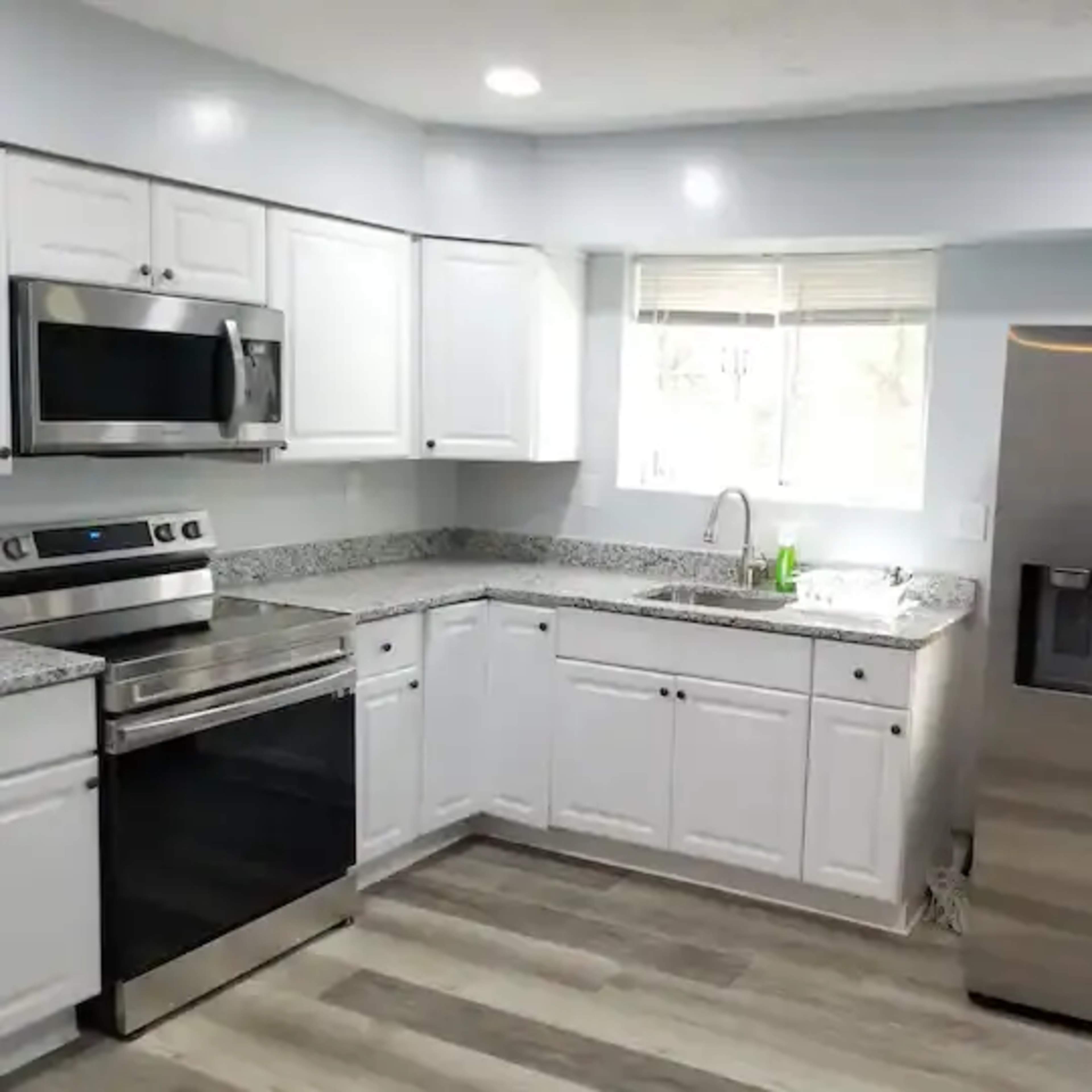 A modern kitchen featuring white cabinetry, stainless steel appliances, and a granite countertop.