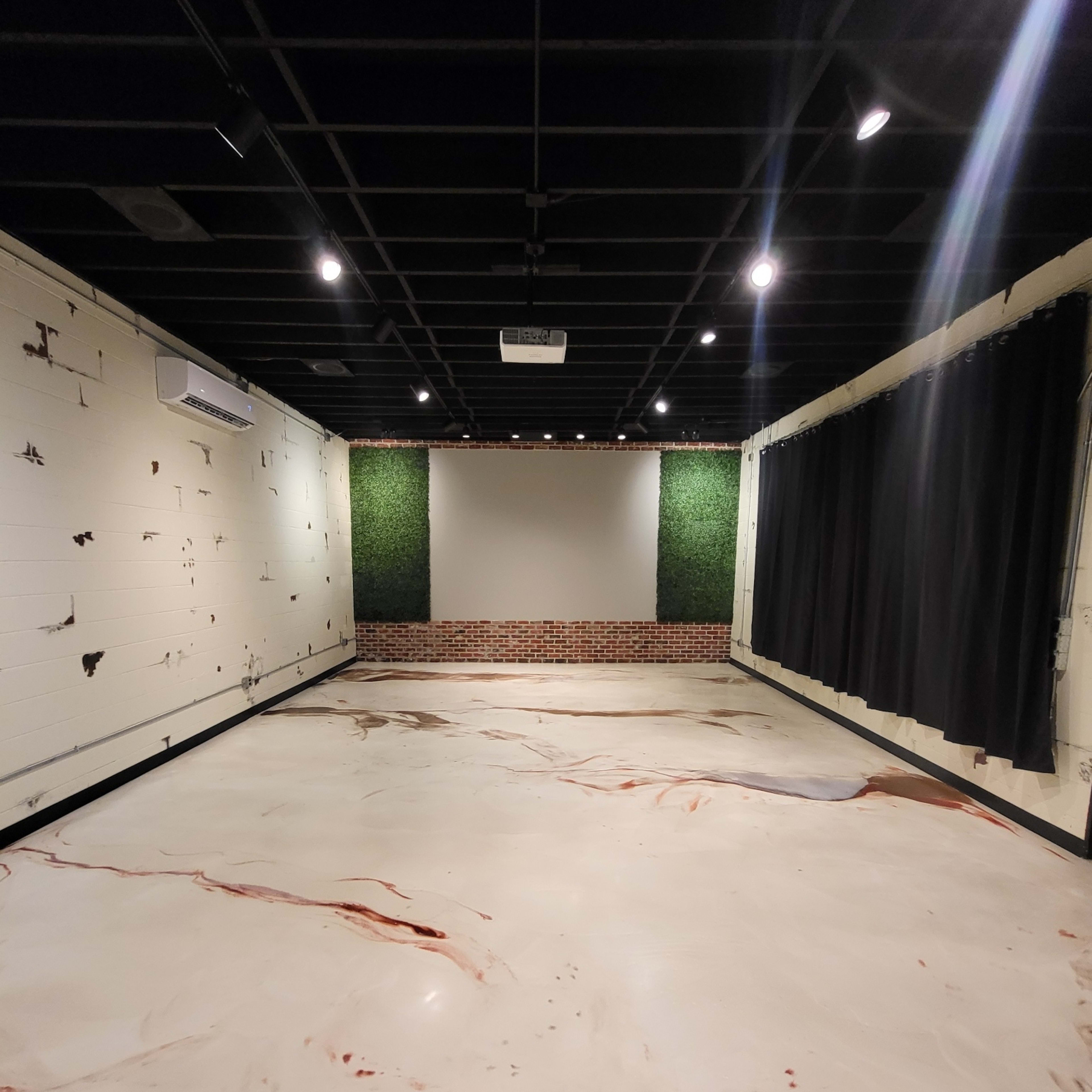 A spacious room with a marbled floor, a brick wall section, green wall decor, and black curtains.
