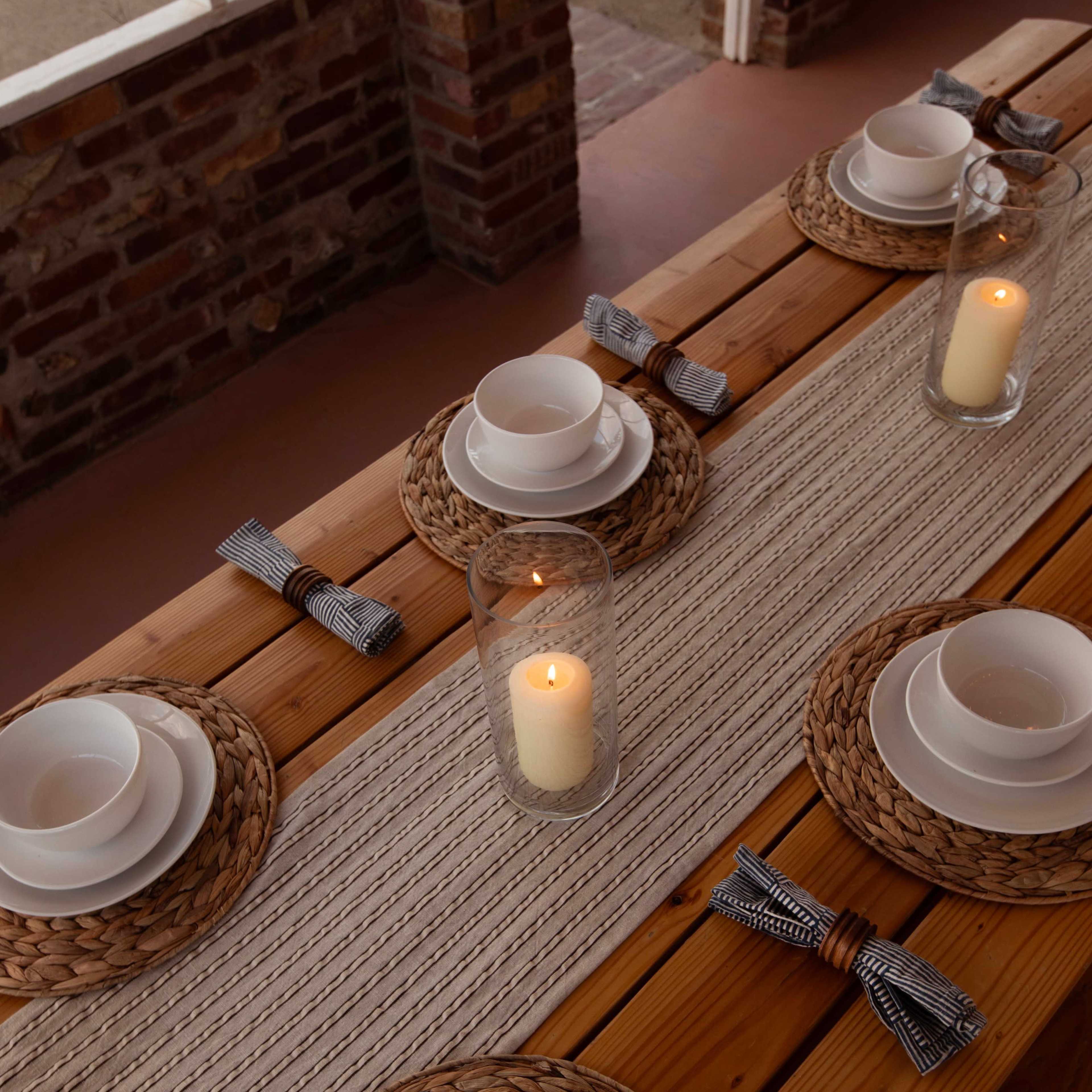 A spacious indoor dining area with wooden tables set for a meal, large windows providing a view of an outdoor fire pit and surrounding greenery.