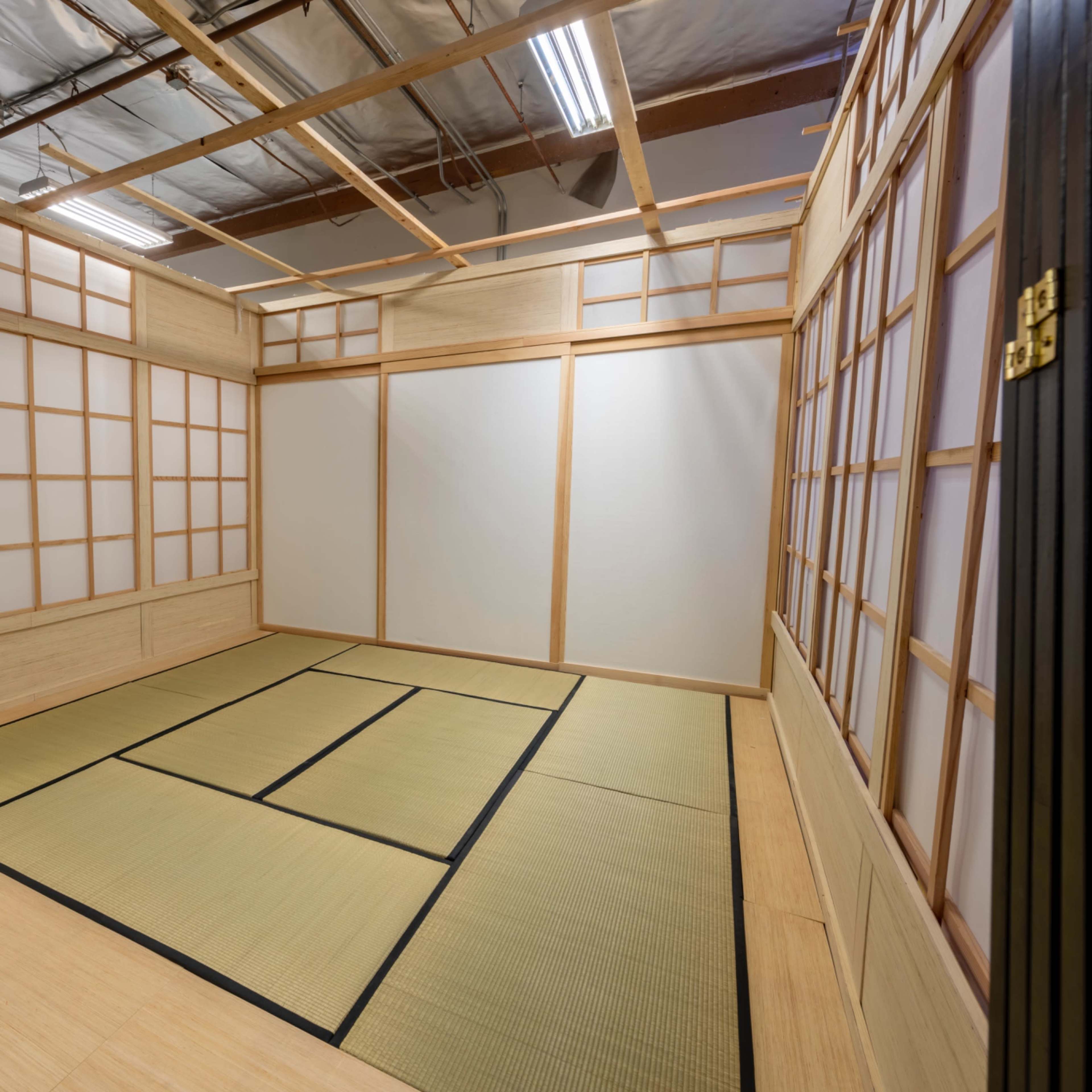 A minimalist room with wooden walls, tatami flooring, and shoji screens.