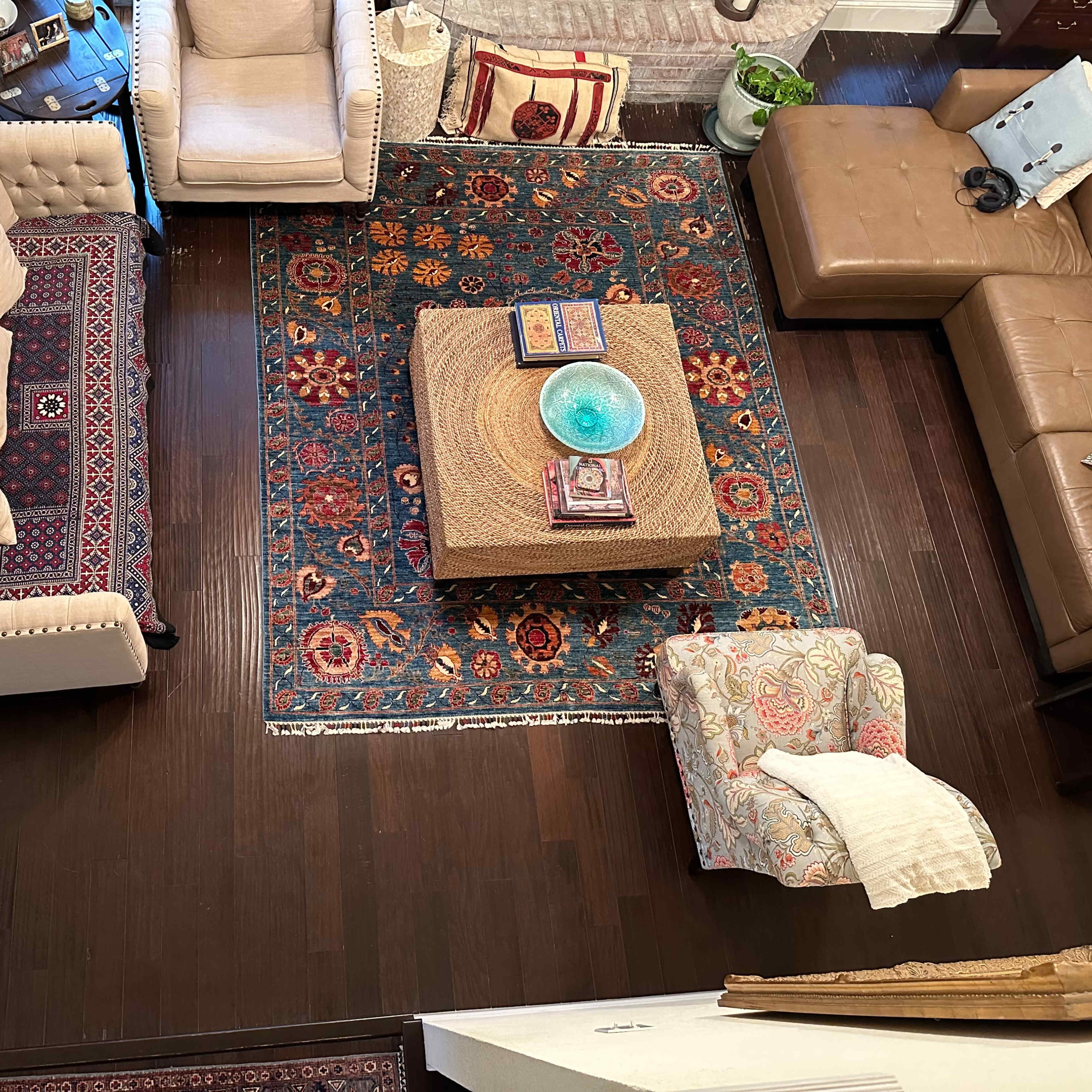 A living room with a large area rug, a coffee table in the center, and various upholstered furniture arranged around it.