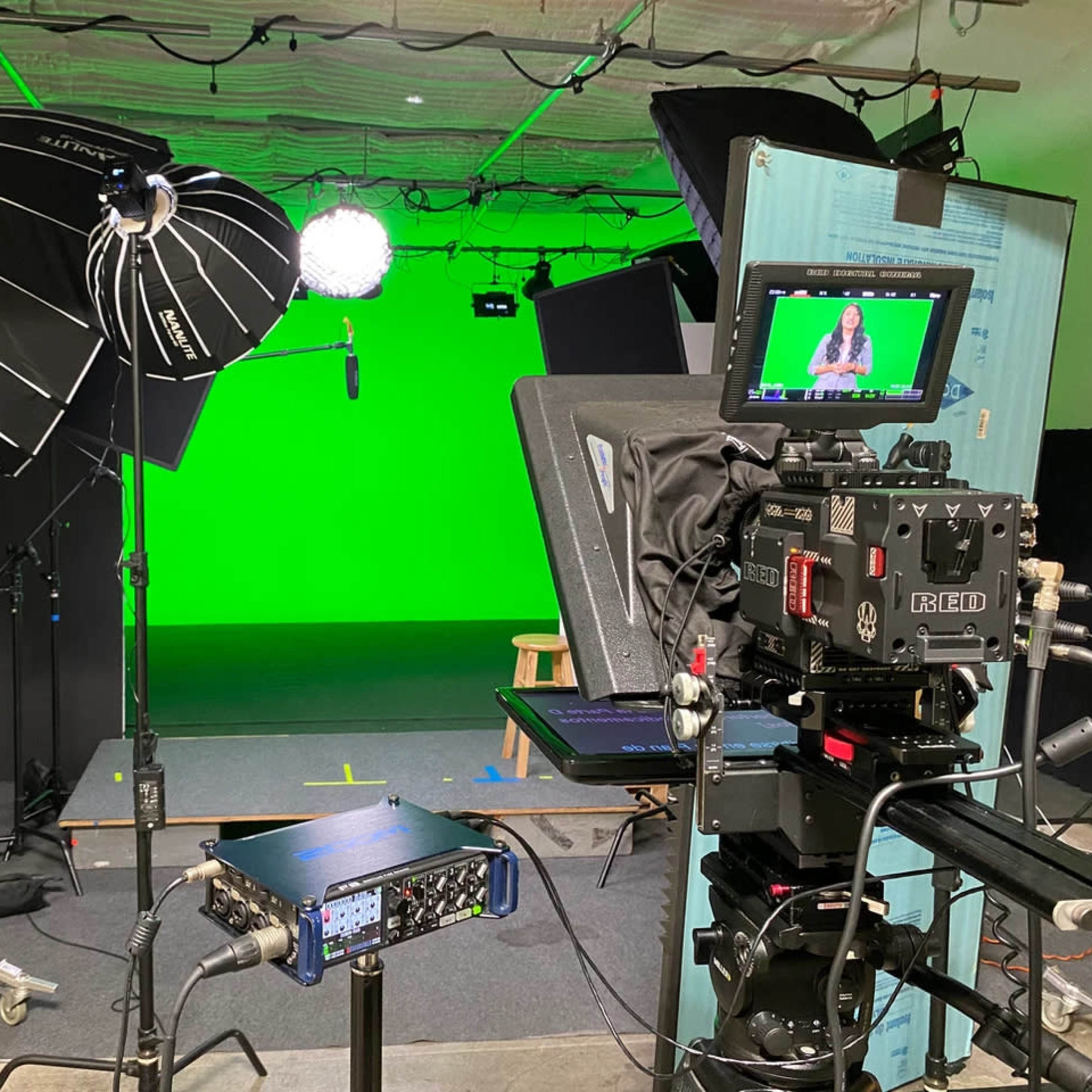 A television studio setup features lighting equipment and a green screen backdrop.