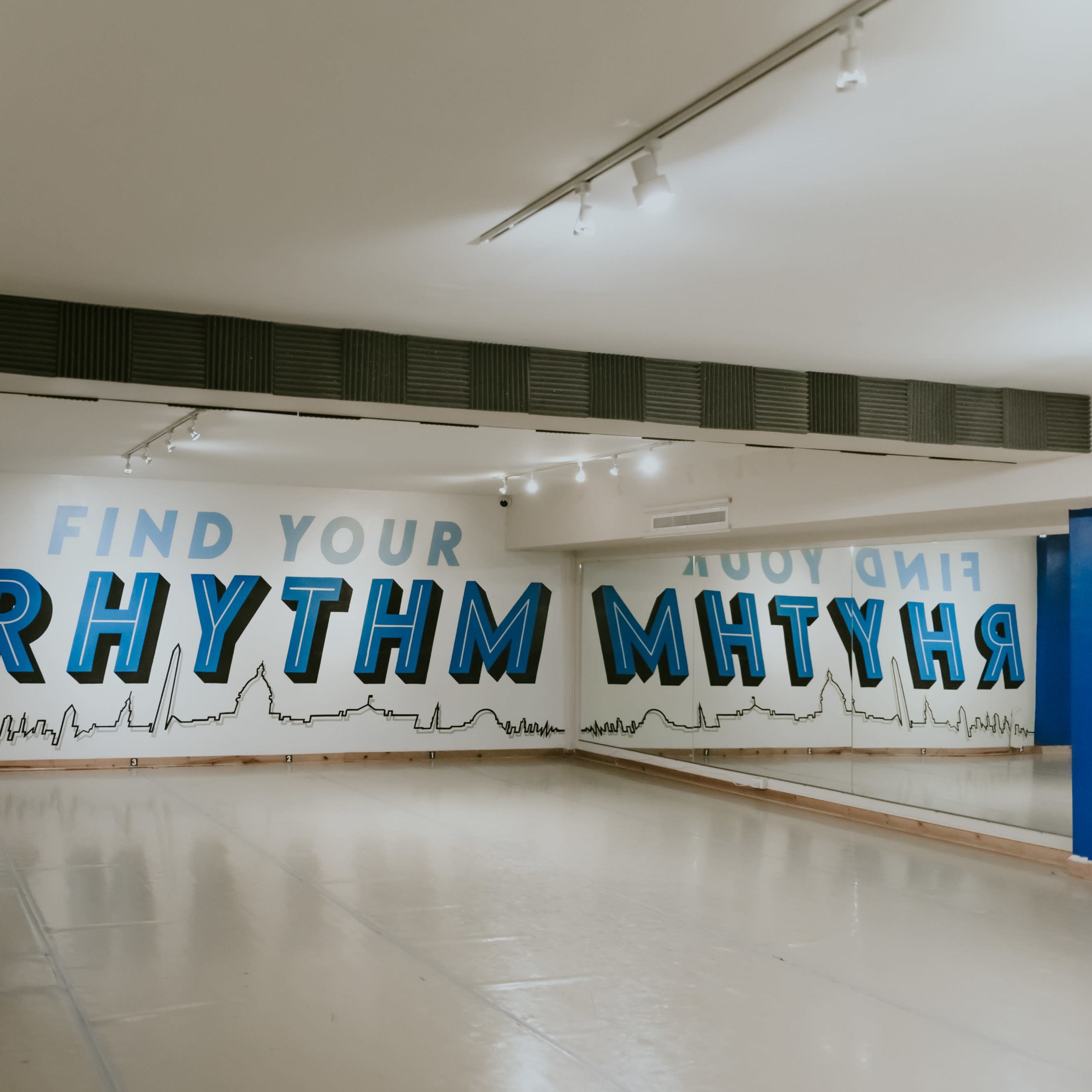 A dance studio with a mirrored wall and a mural that reads "FIND YOUR RHYTHM."