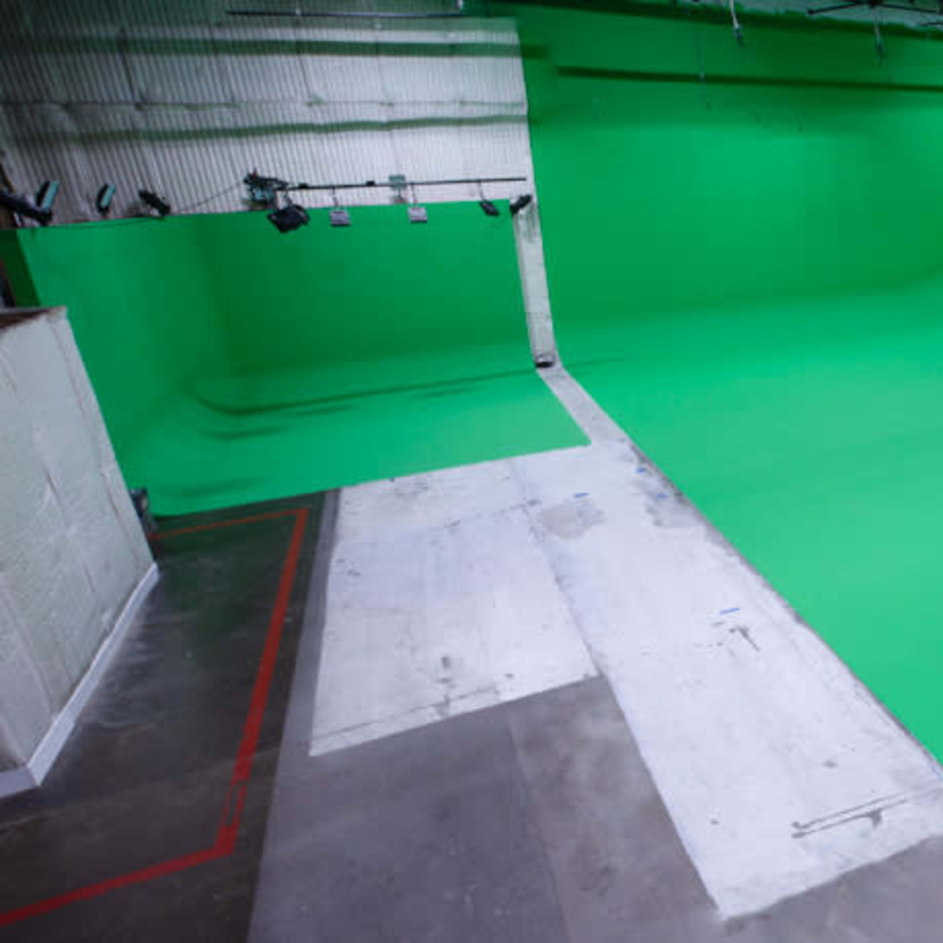 A large green screen studio with a smooth, flat floor and a green backdrop.