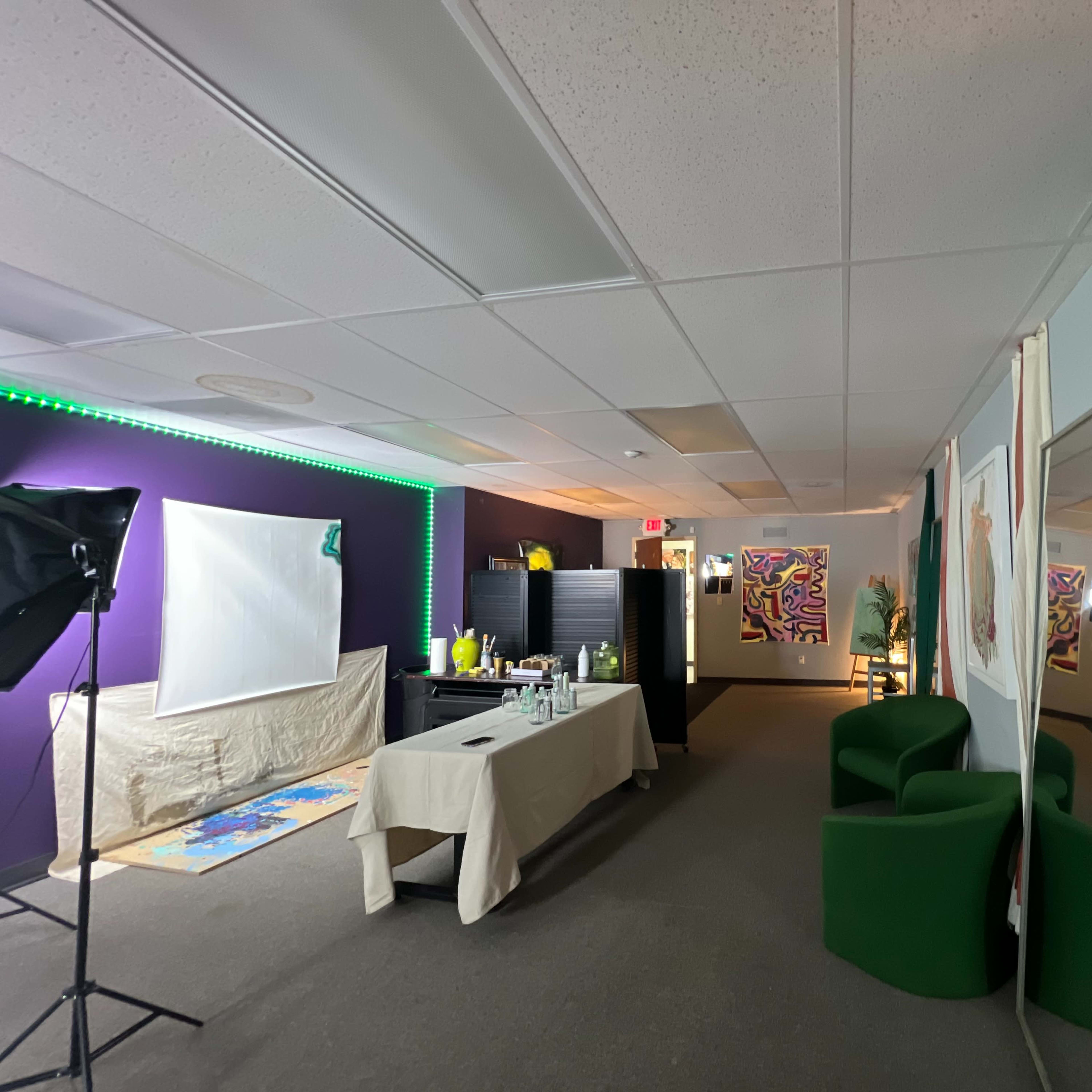 A modern office space with green furniture, a table set up with various items, and colorful artwork displayed on the walls.