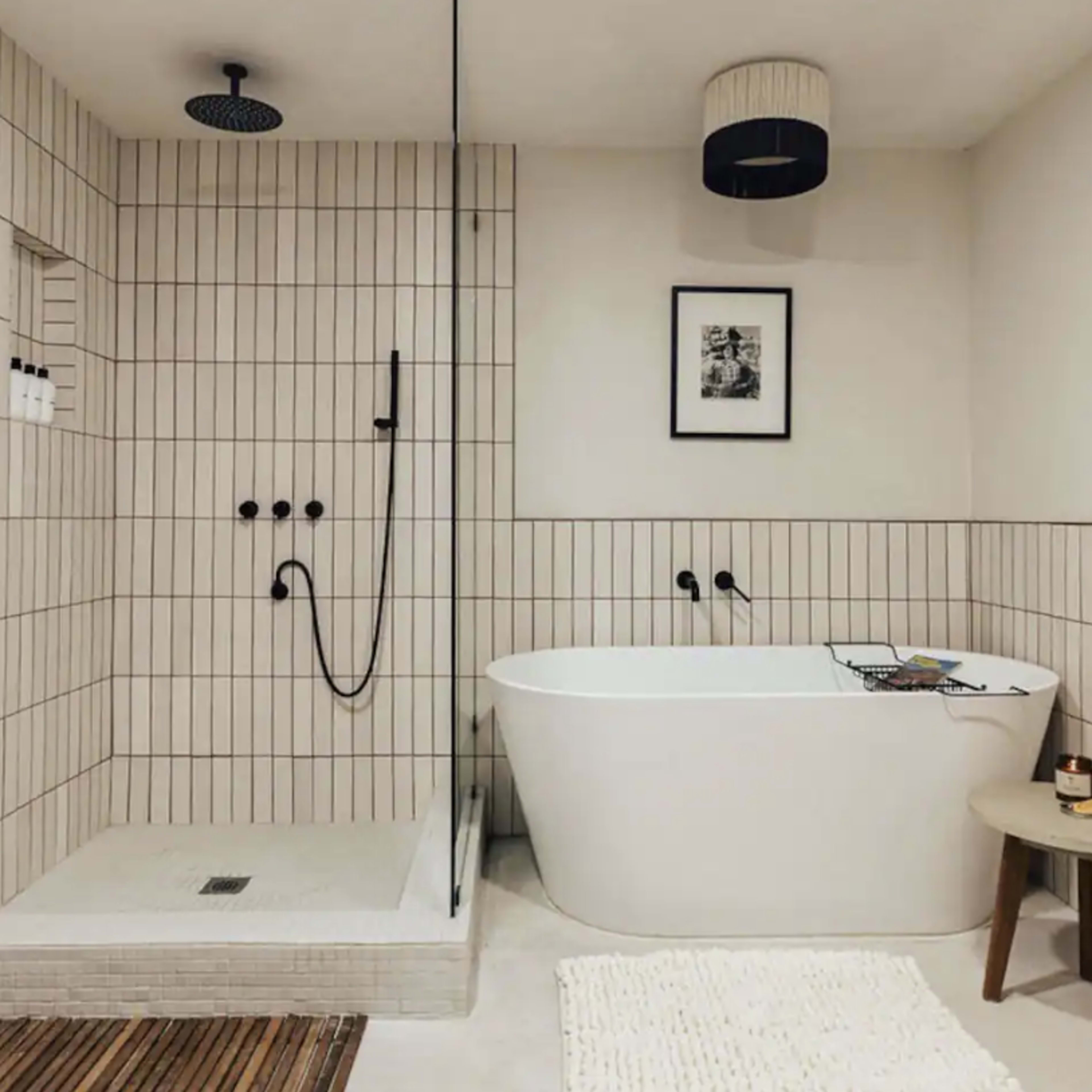 The bathroom features a freestanding bathtub, a walk-in shower with a rainfall showerhead, and tiled walls with dark accents.