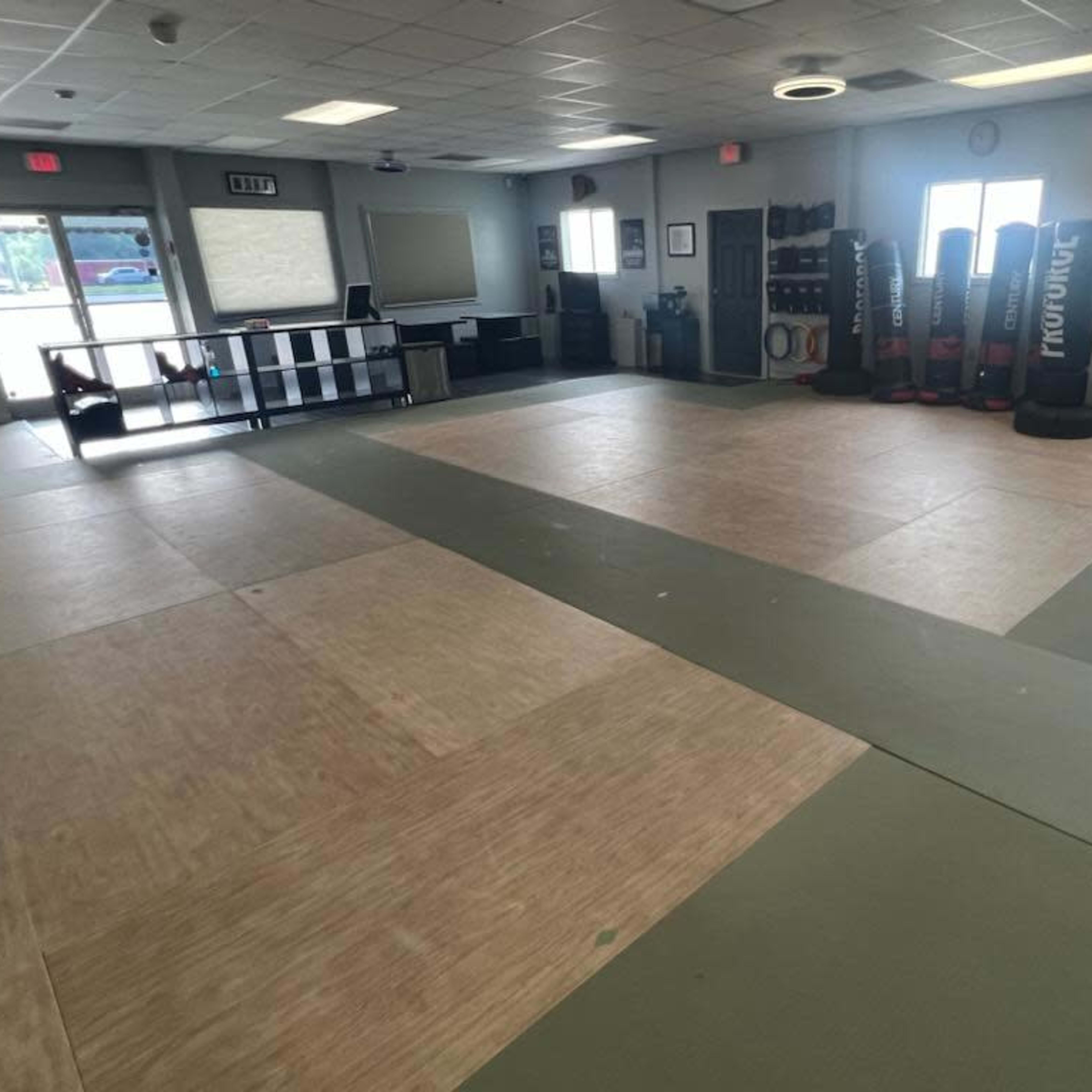 An empty training room with padded flooring and exercise equipment lined against the walls.