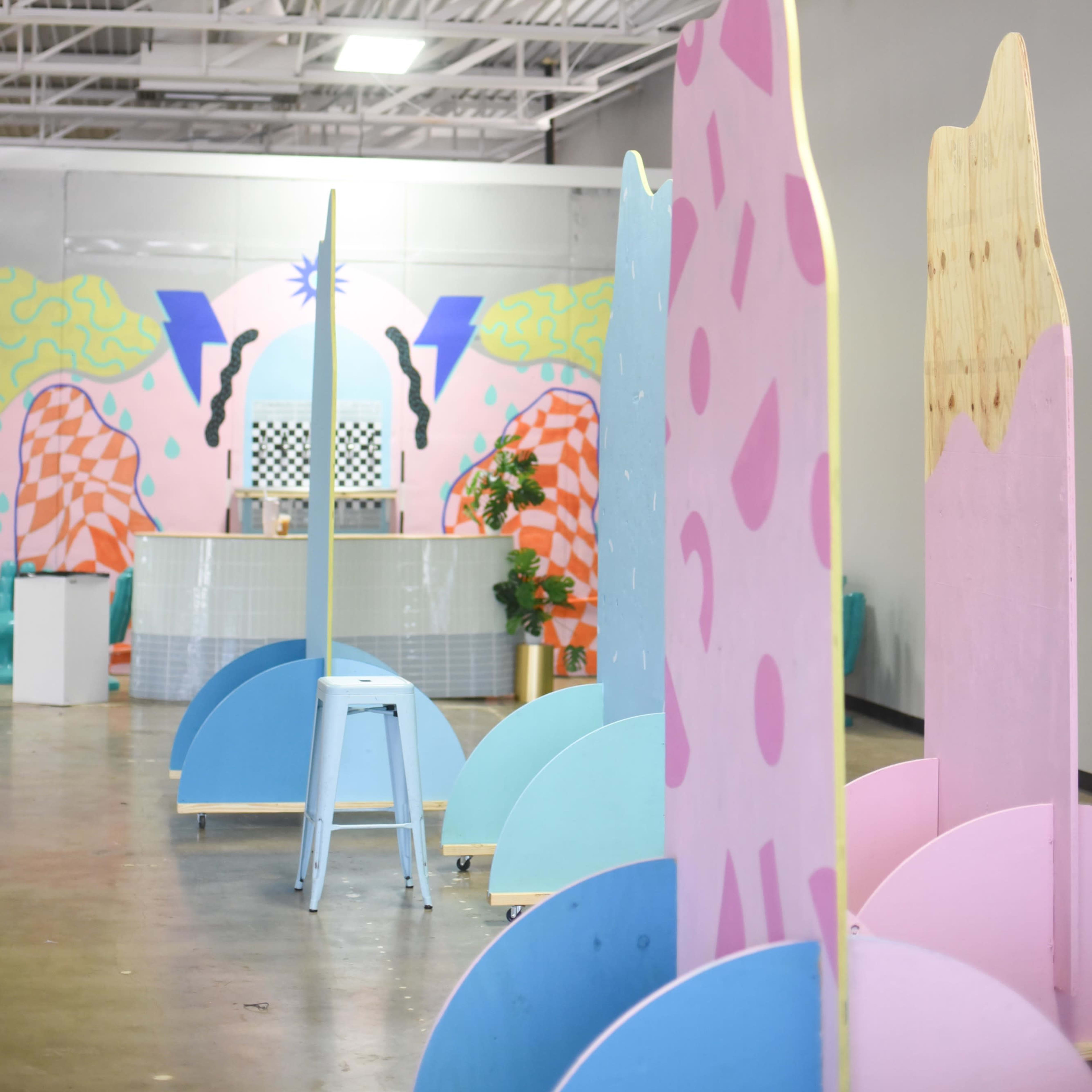 A spacious interior with brightly colored, abstract partition panels and a patterned backdrop featuring geometric designs.