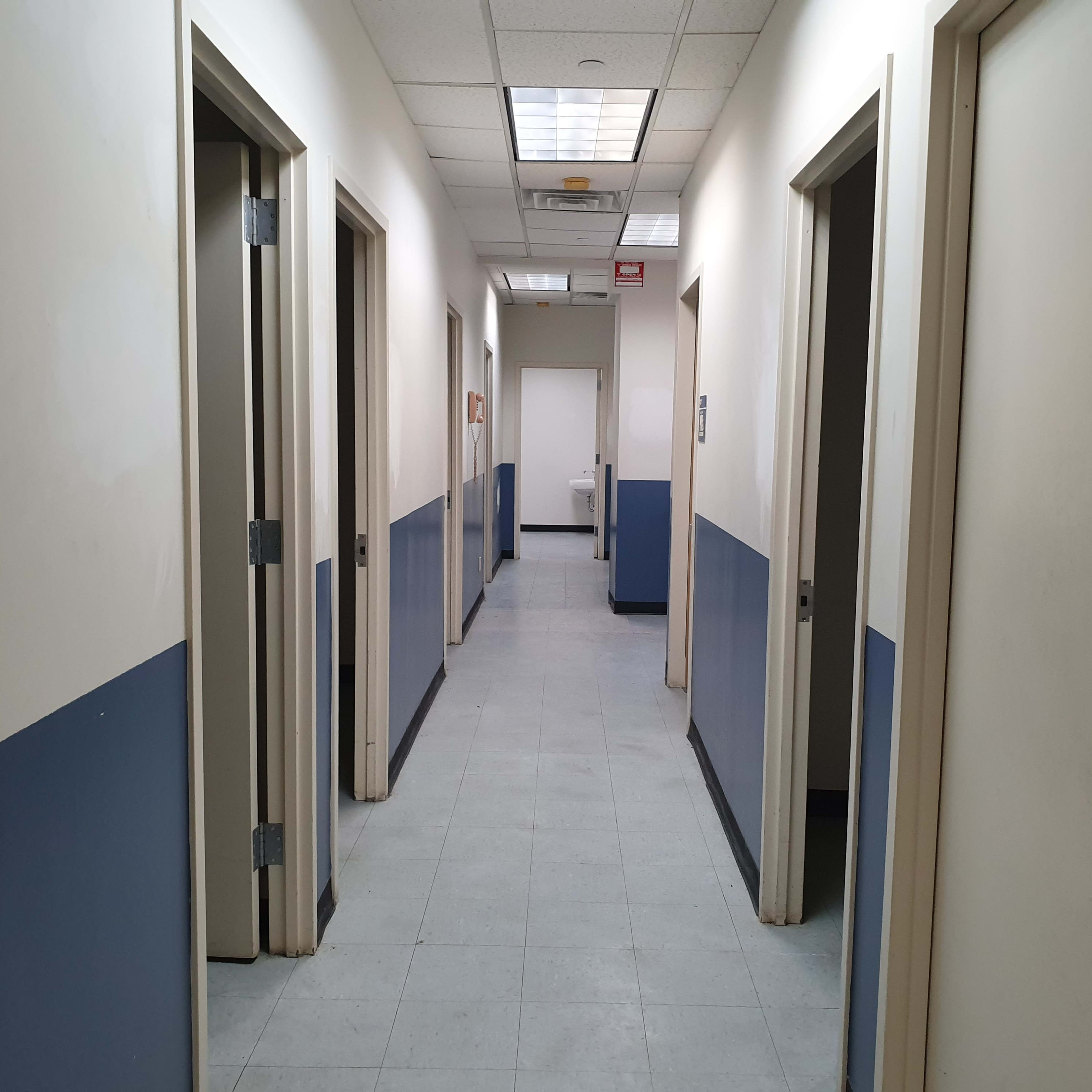 A long corridor with several doors on either side and a door at the end.