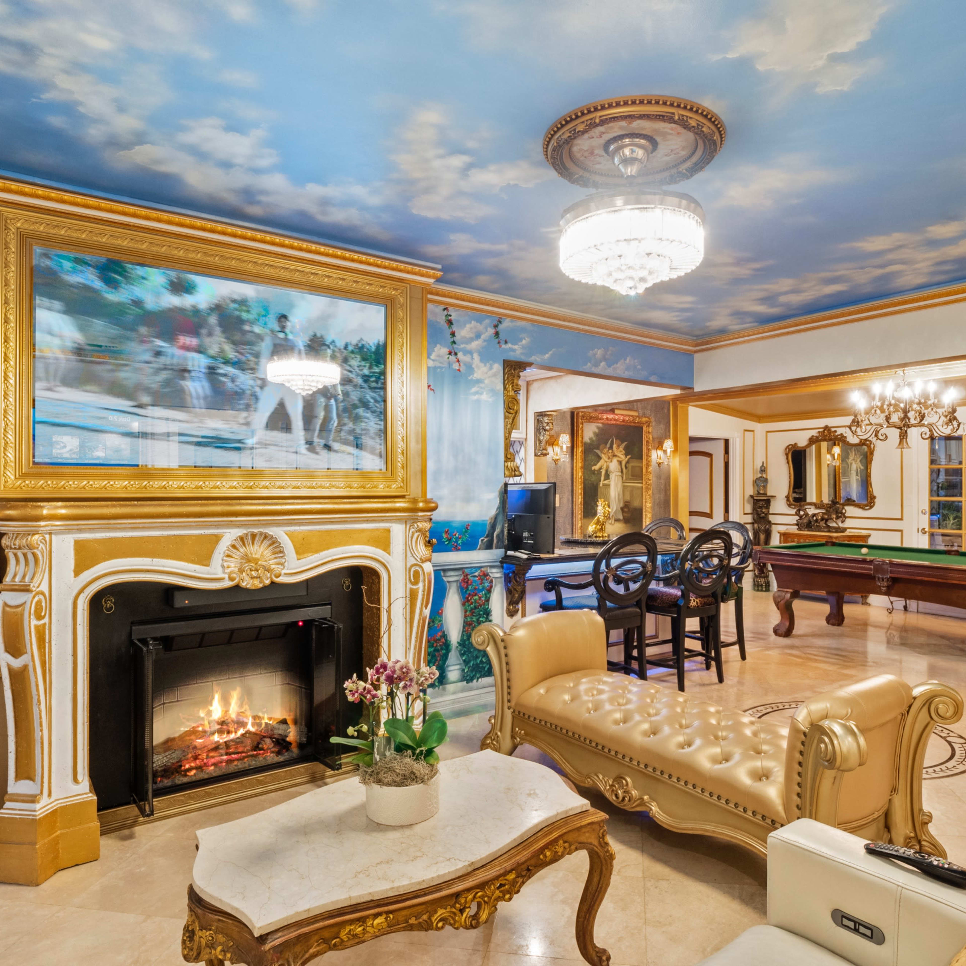 The interior features a lavish room with a fireplace, ornate furnishings, a billiards table, and a painted ceiling depicting clouds.