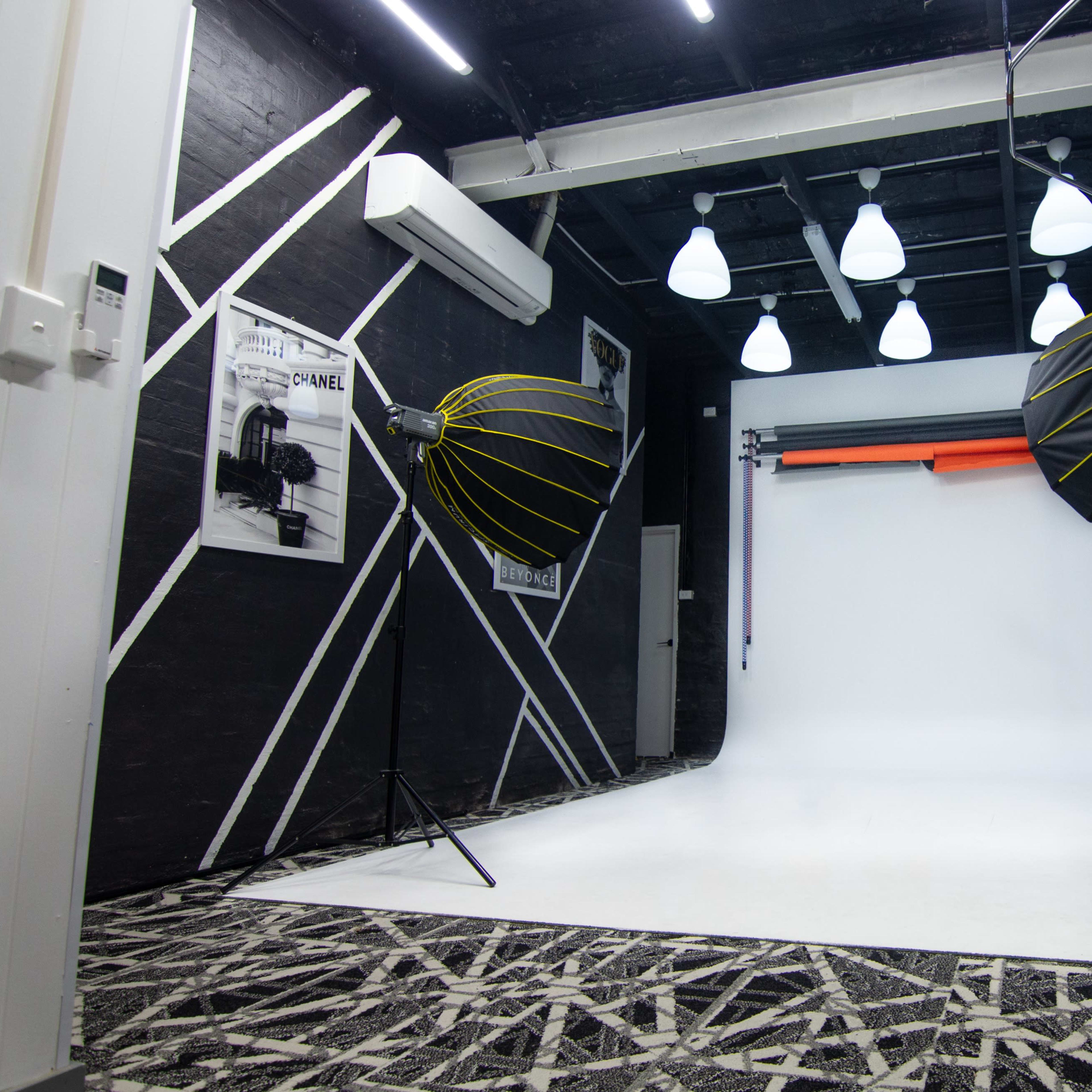 A photography studio featuring a white backdrop, two large octagonal softboxes, and patterned flooring.