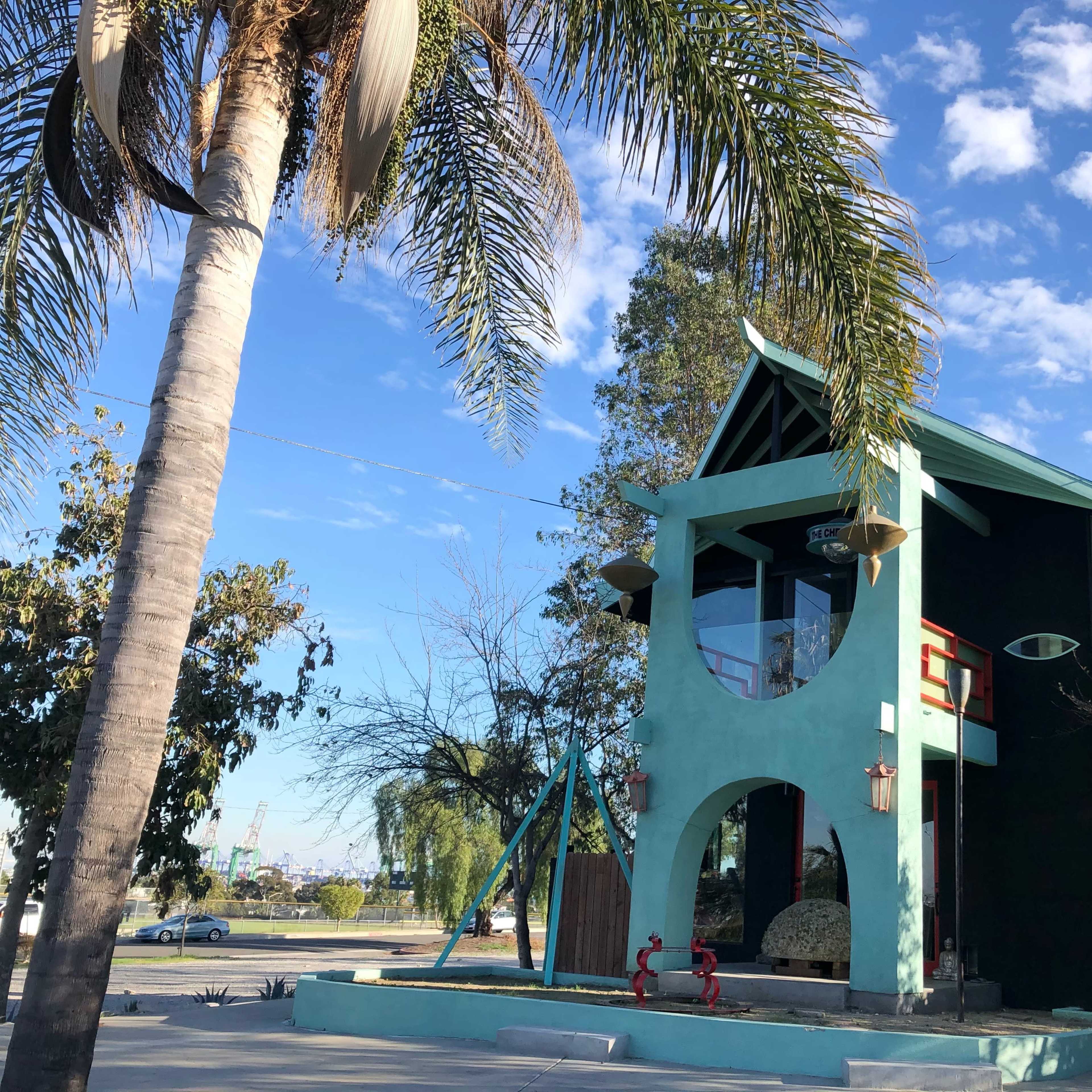 A colorful, modern building with an eye-shaped detail, surrounded by palm trees and a clear blue sky.