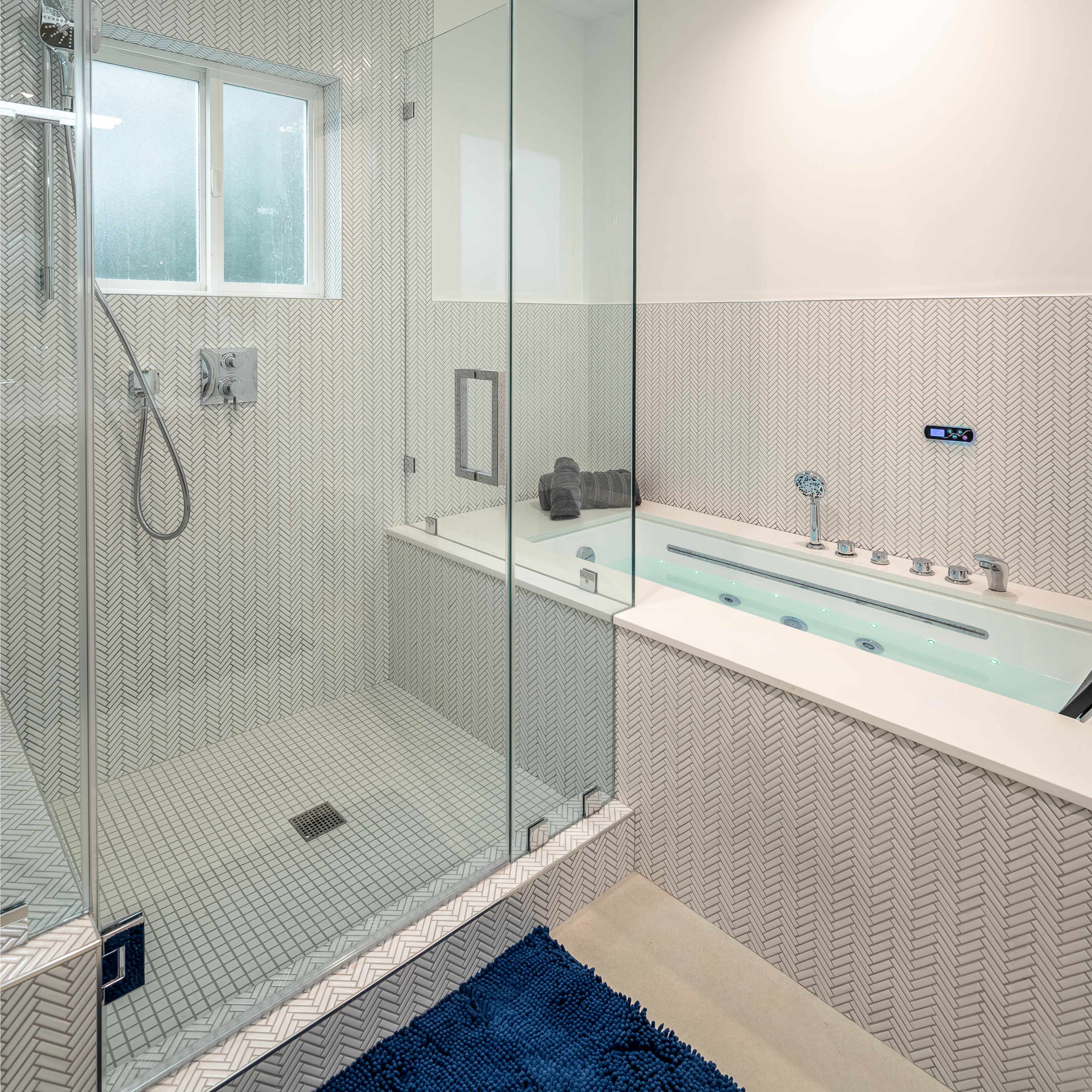 A modern bathroom featuring a glass-enclosed shower and a freestanding bathtub with a patterned tile backsplash.