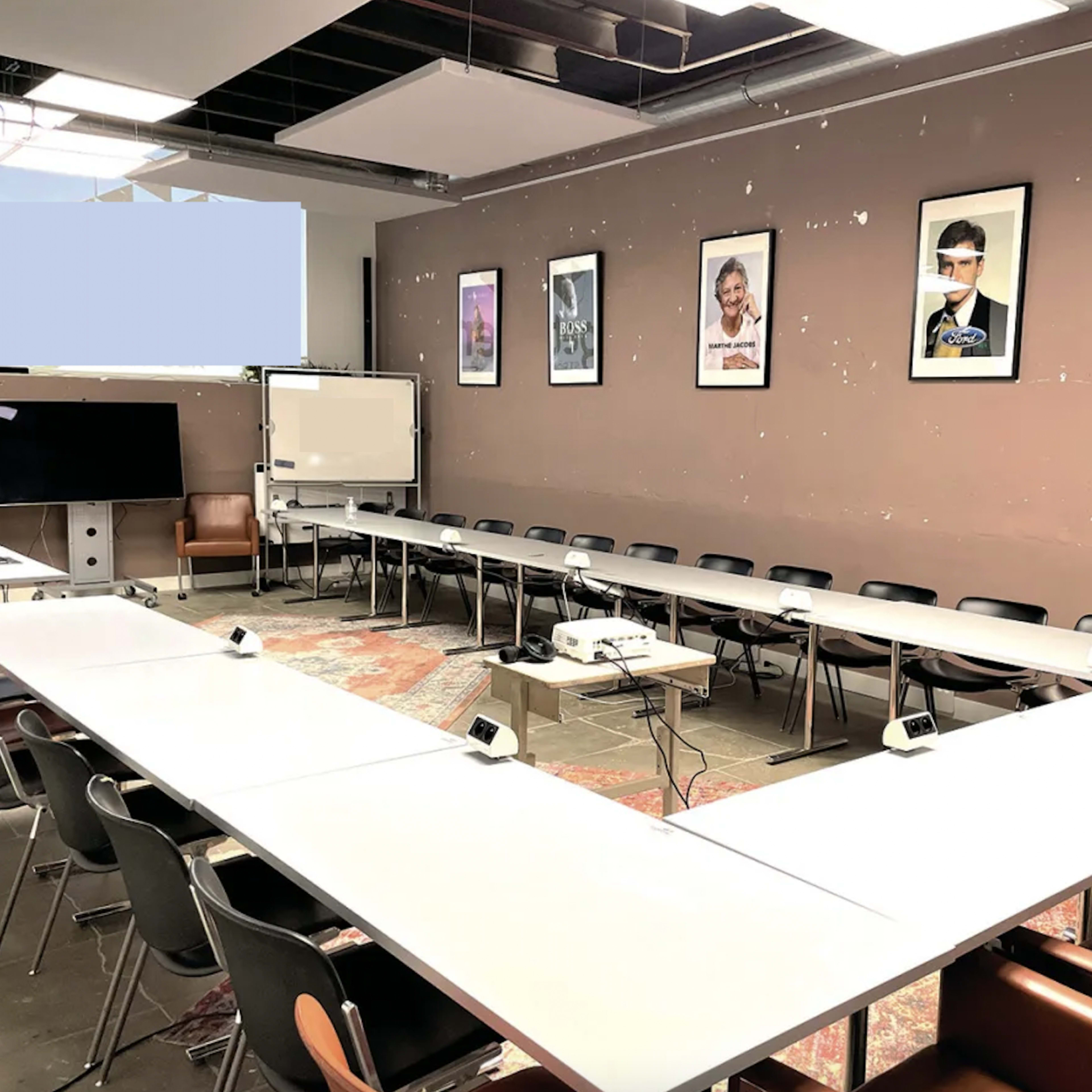 A conference room with a large U-shaped table, chairs around it, and posters on the walls.