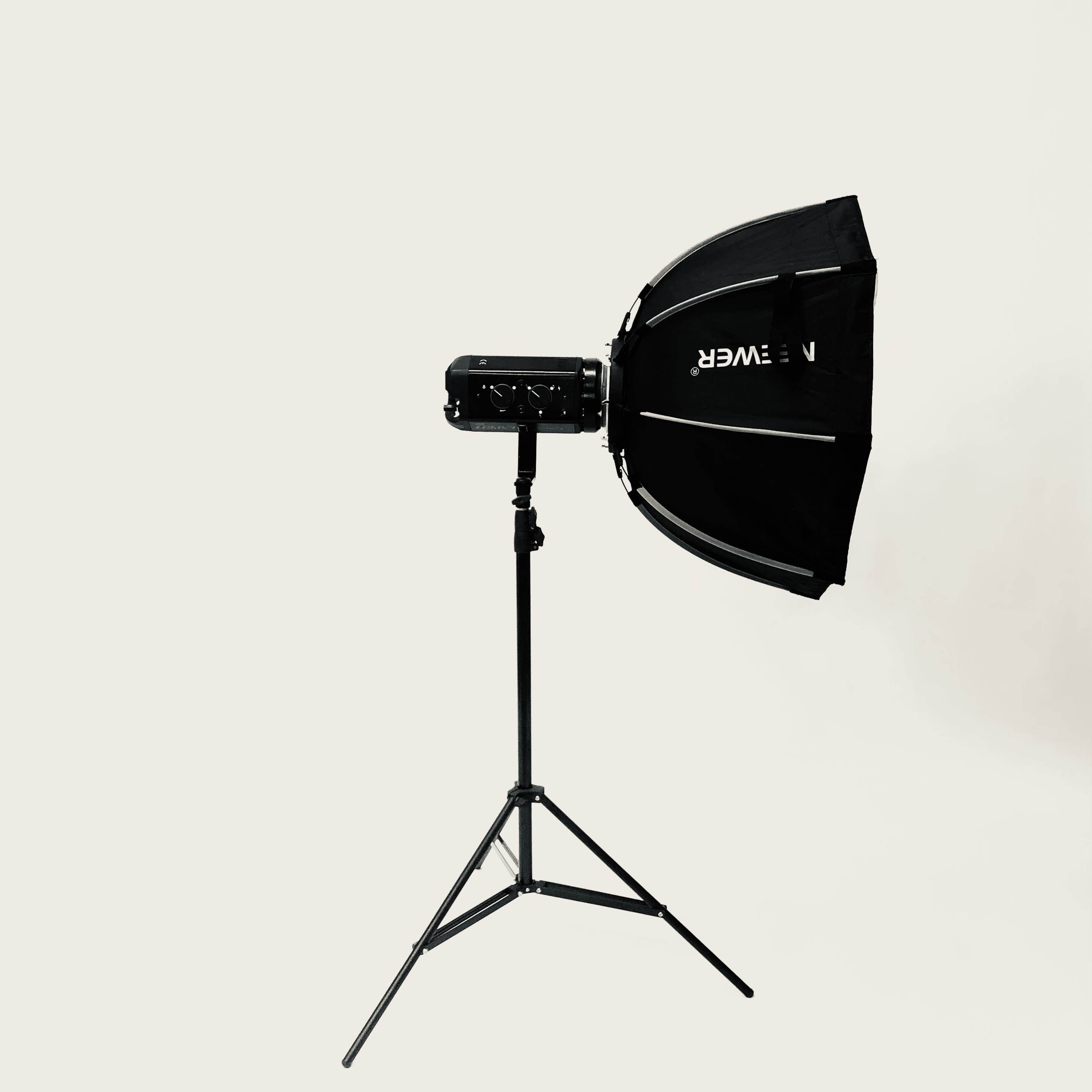 A professional studio light with a softbox is mounted on an adjustable stand against a plain background.