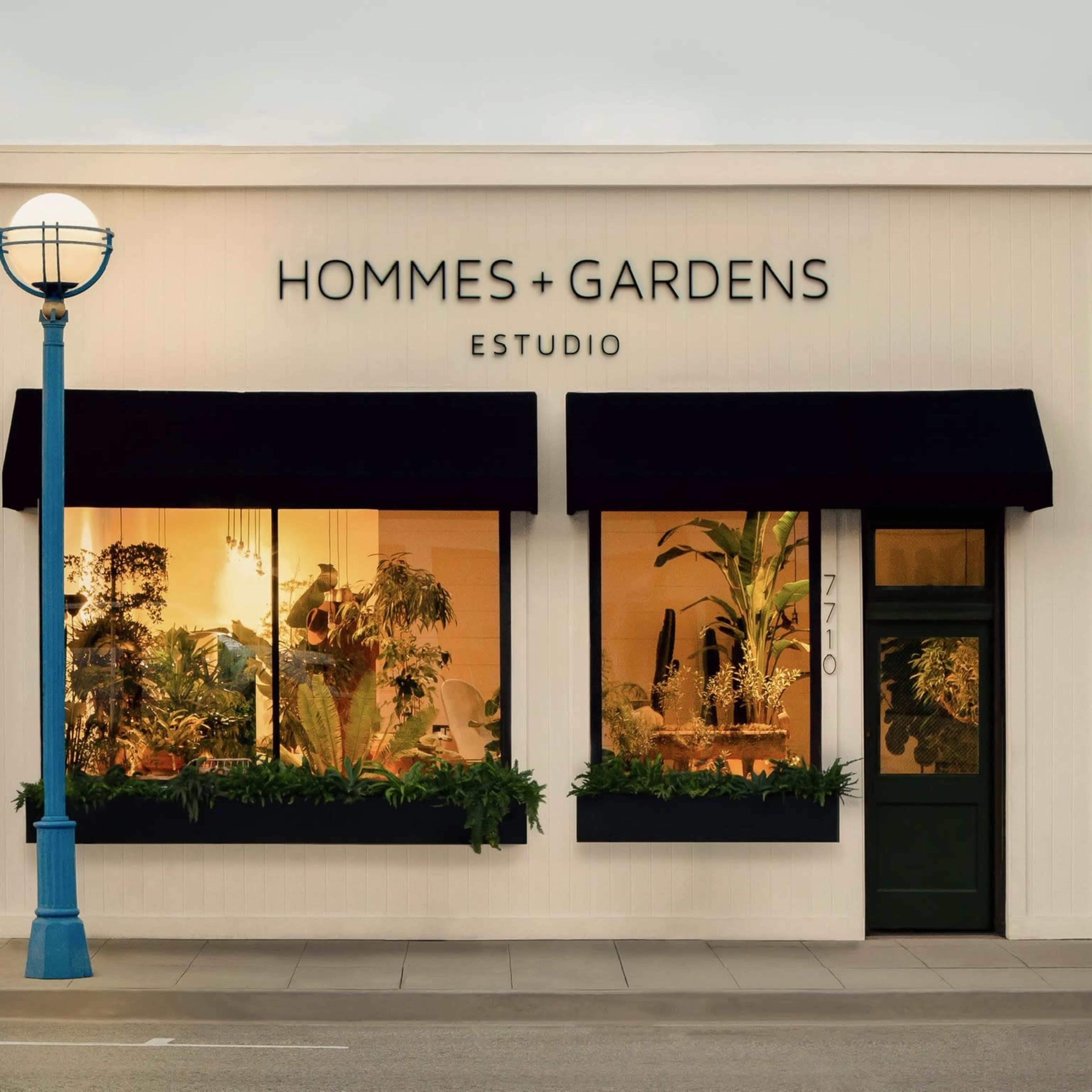 A storefront features the name "HOMMES + GARDENS ESTUDIO" above large windows adorned with plants.