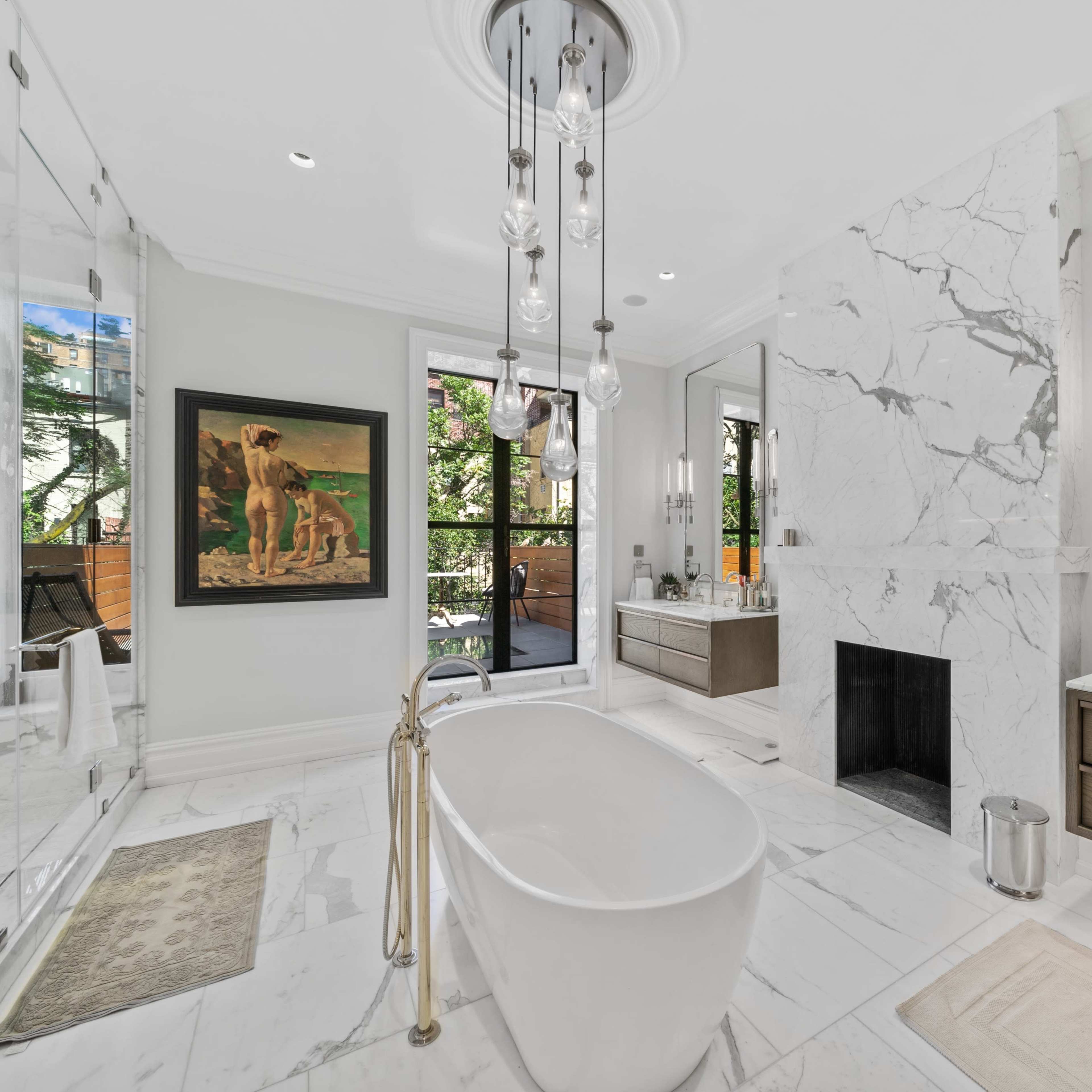 A modern bathroom featuring a freestanding bathtub, a glass shower enclosure, a double vanity with dark wood cabinetry, and large marble tiles, all complemented by natural light from windows.