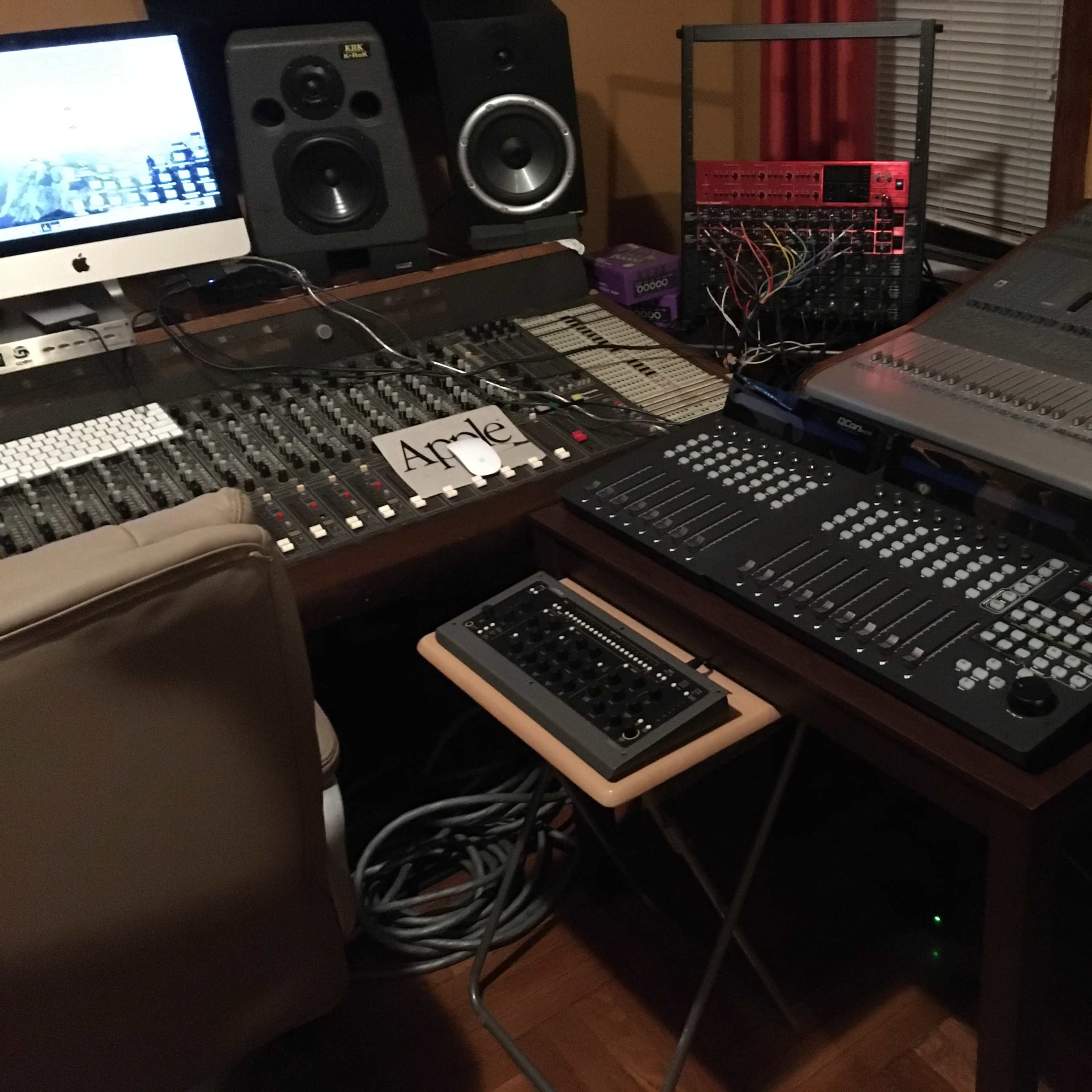 A music production setup featuring a mixing console, computer, and various audio equipment.