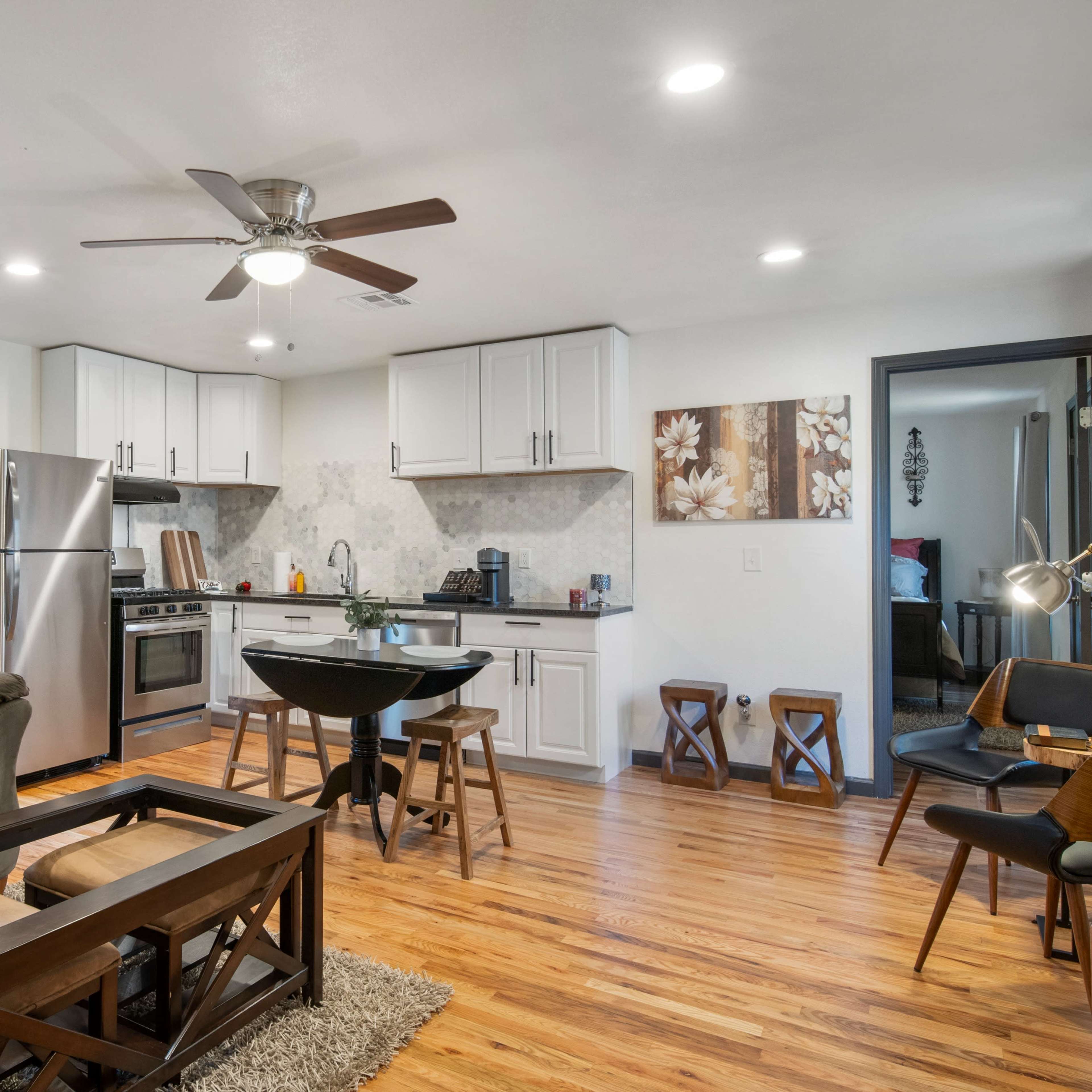 A modern living space featuring a kitchen with stainless steel appliances, a dining area, and a comfortable seating area with a sofa and coffee table.