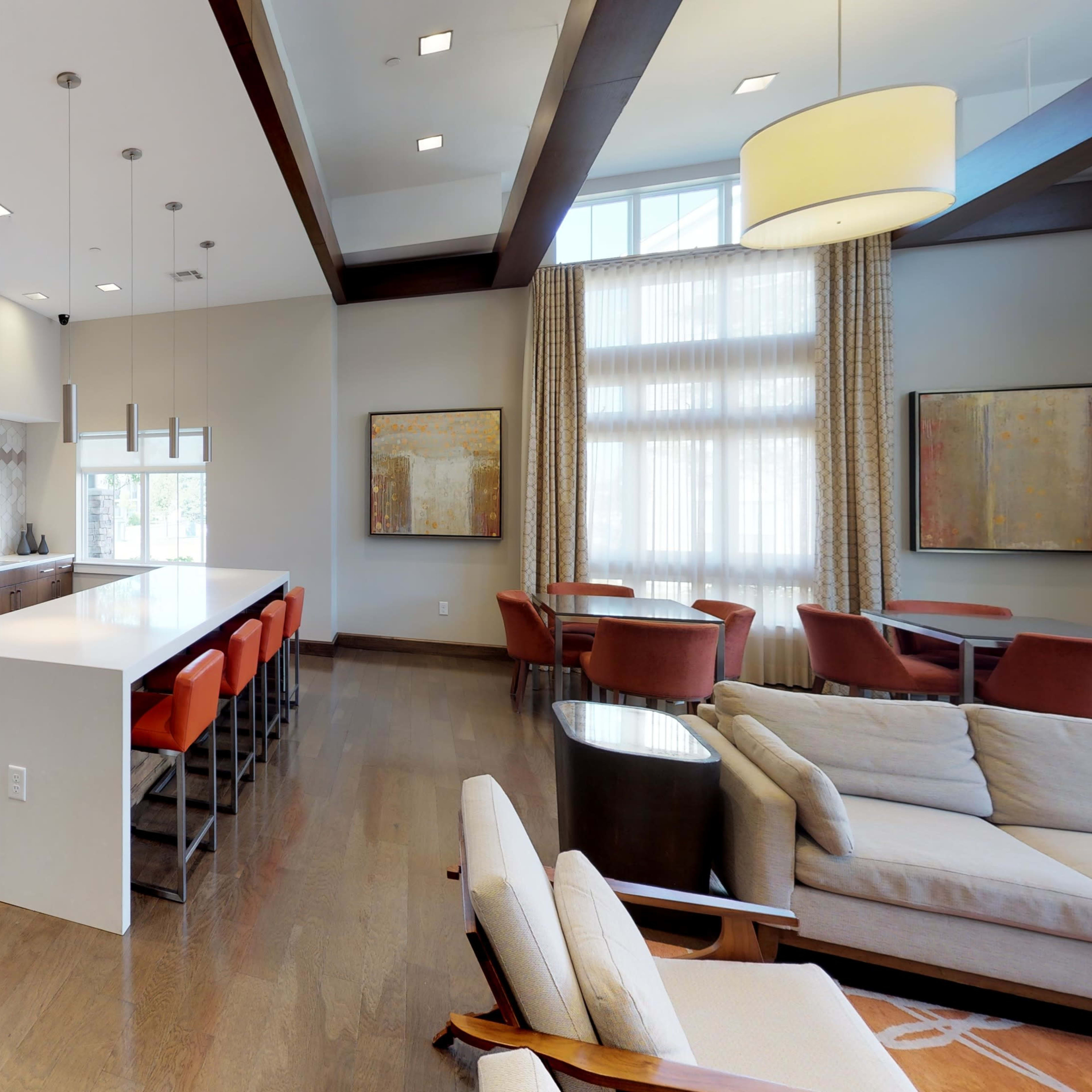 A modern interior space with a kitchen island, seating area, and large windows letting in natural light.