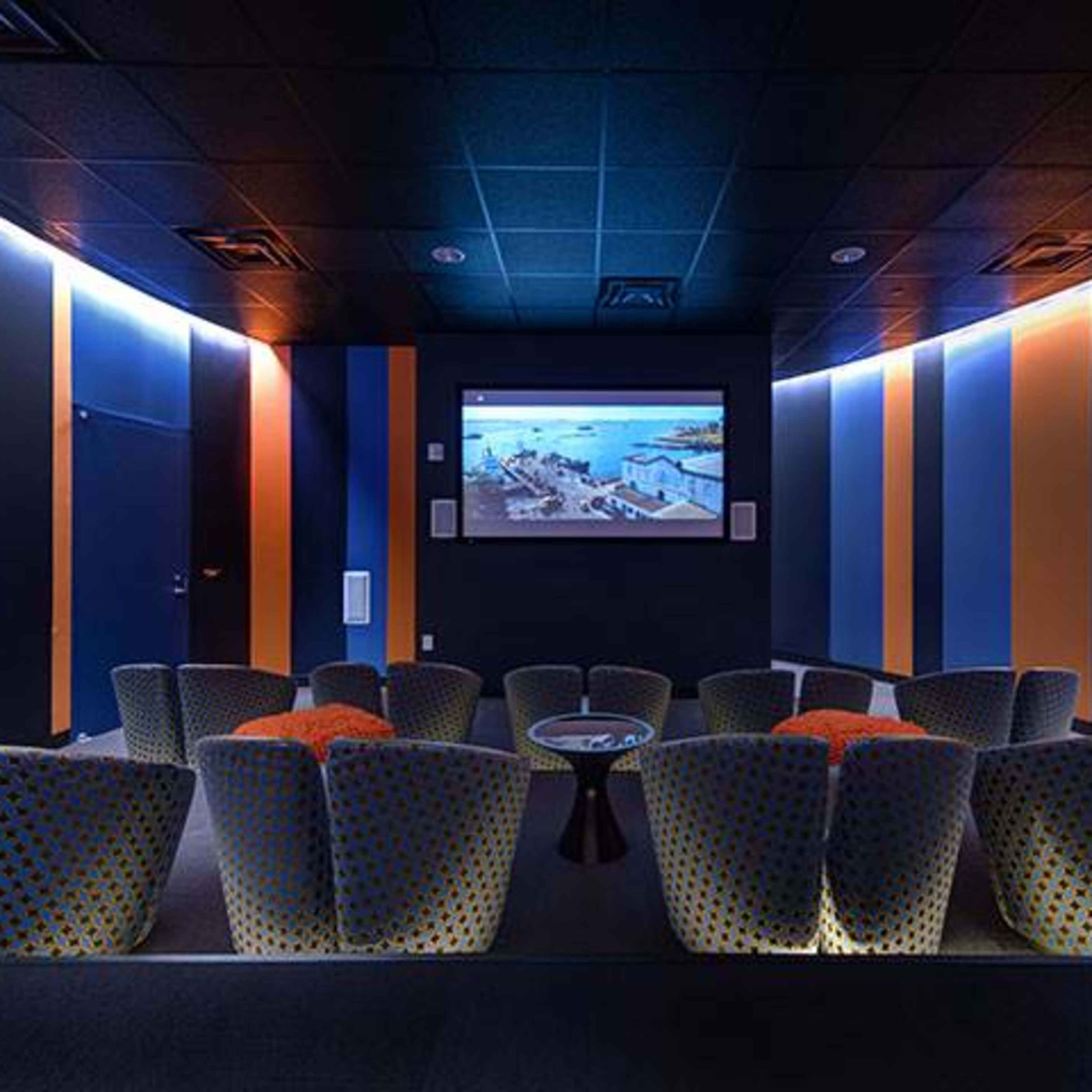 A modern home theater with curved seating, a wall-mounted screen, and striped blue and orange walls.