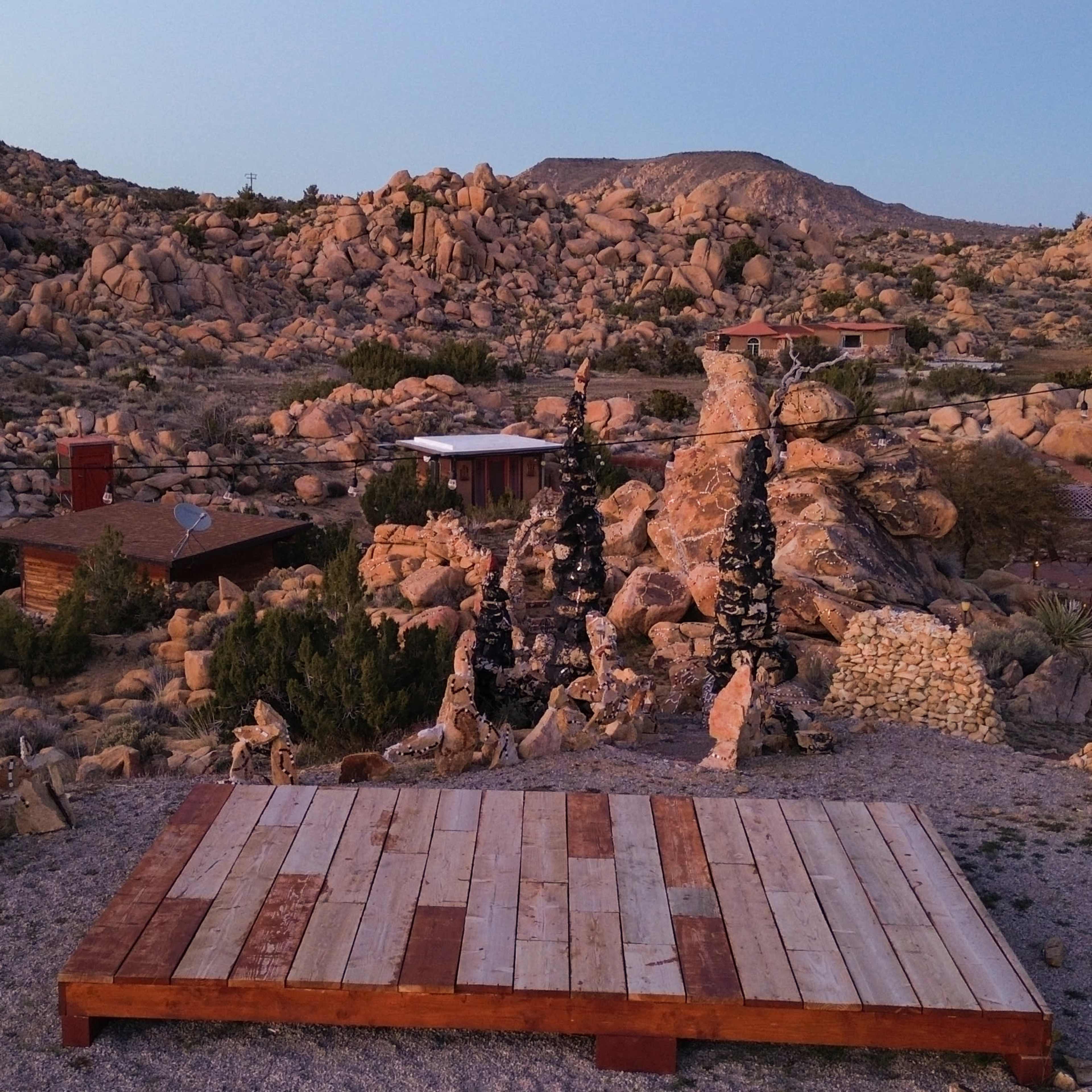A wooden platform surrounded by rocky terrain and sparse vegetation in a desert landscape.