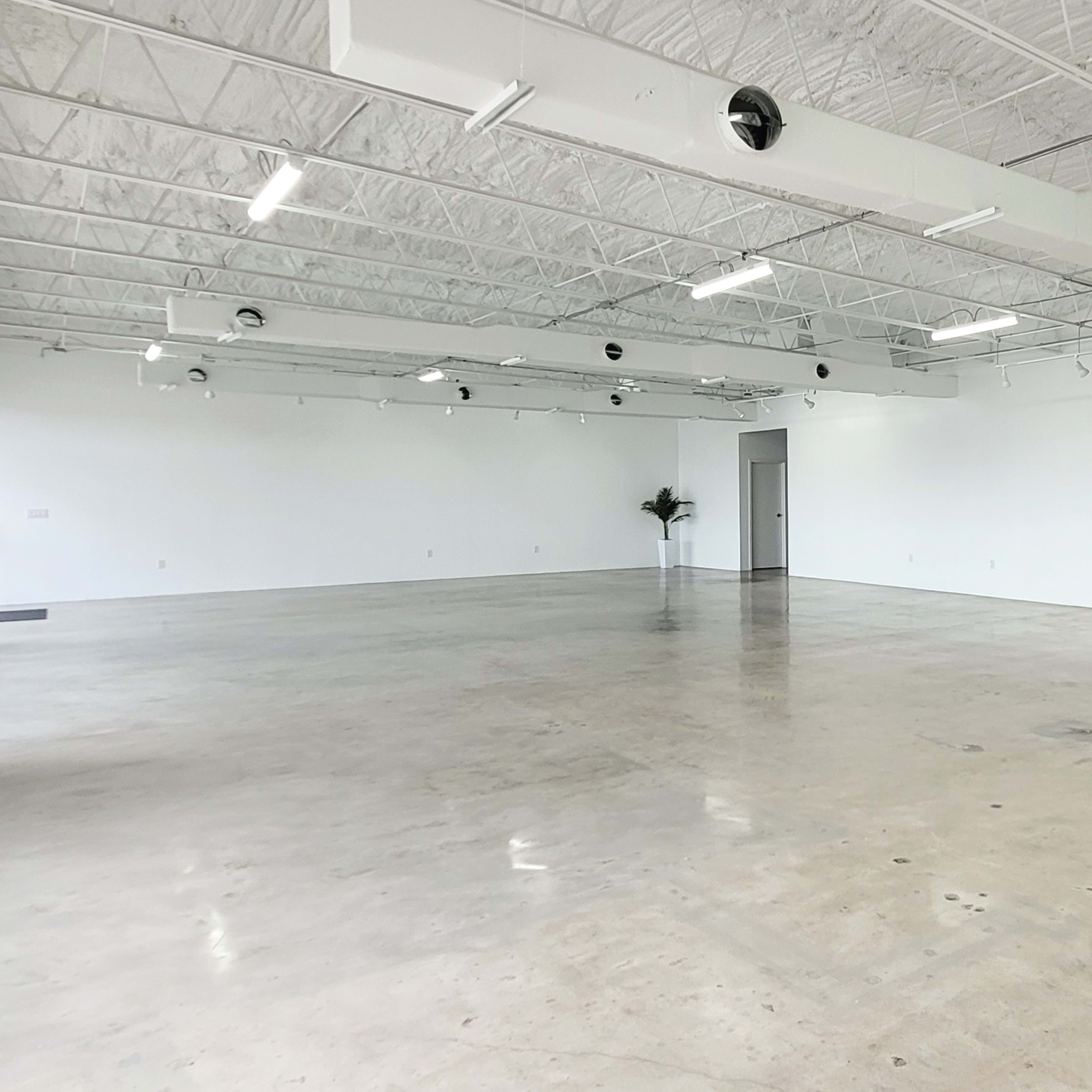 An empty, well-lit commercial space with concrete flooring and white walls.