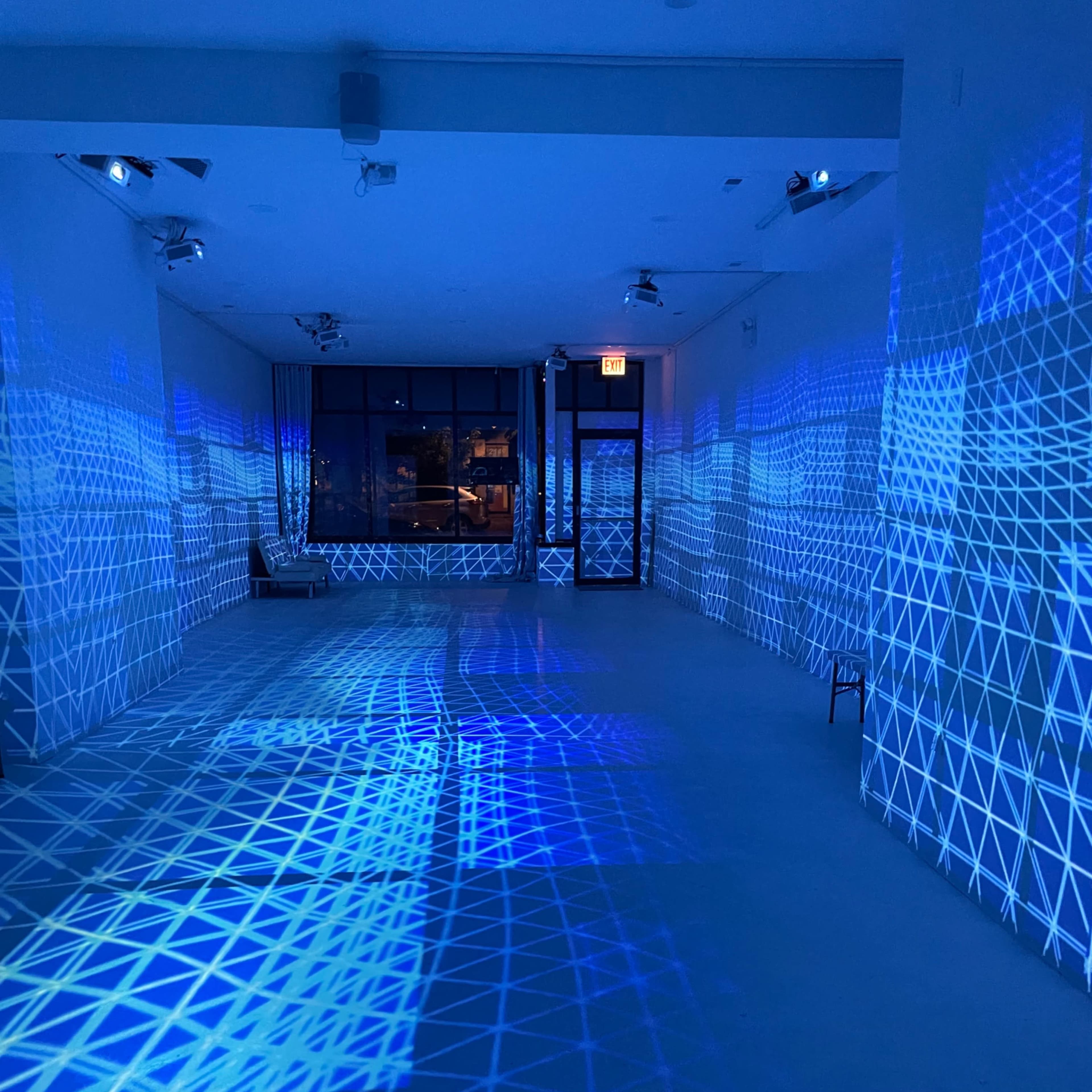 An empty room with blue geometric light patterns projected onto the walls and floor.