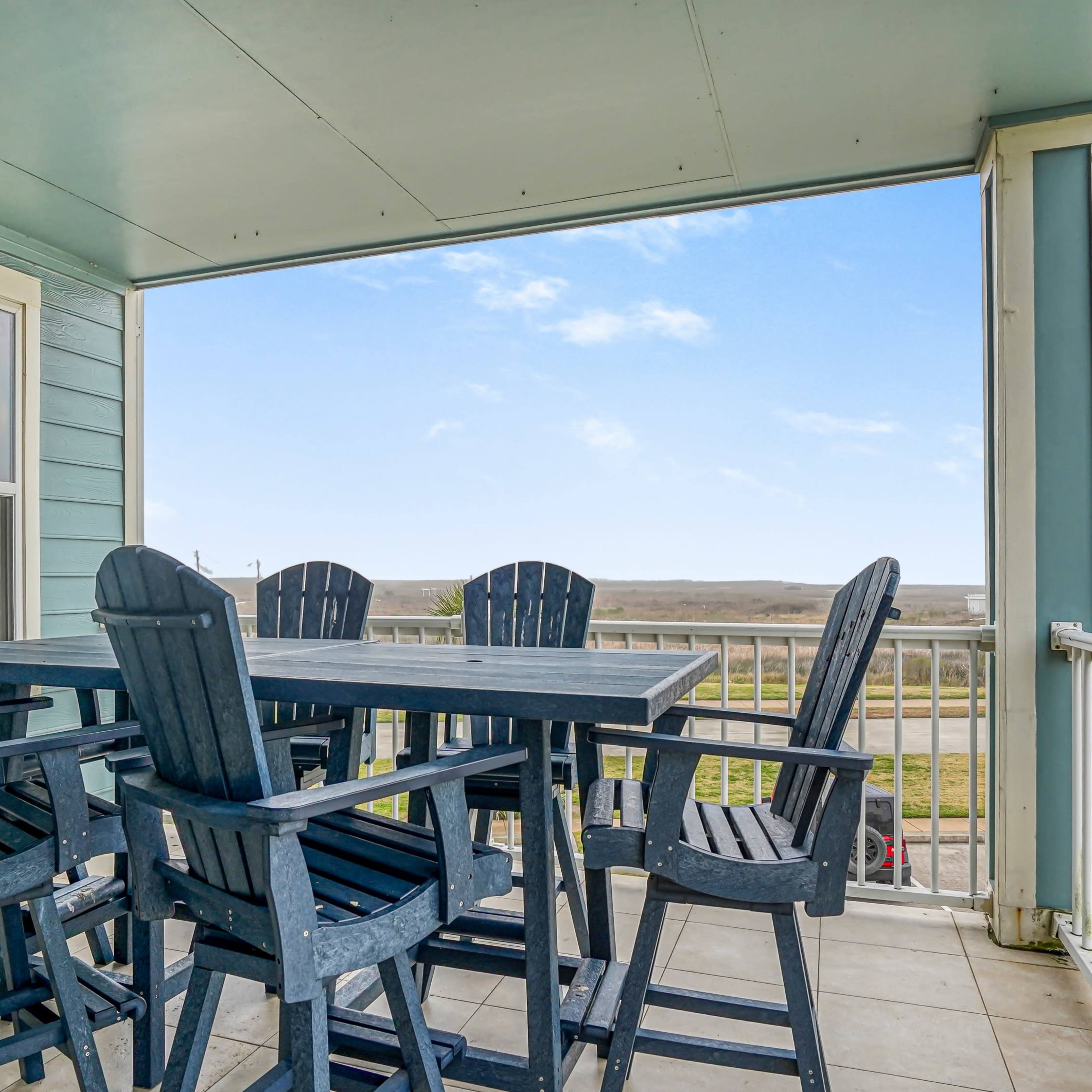 A patio area with a large table and several high-backed chairs overlooking a scenic landscape.