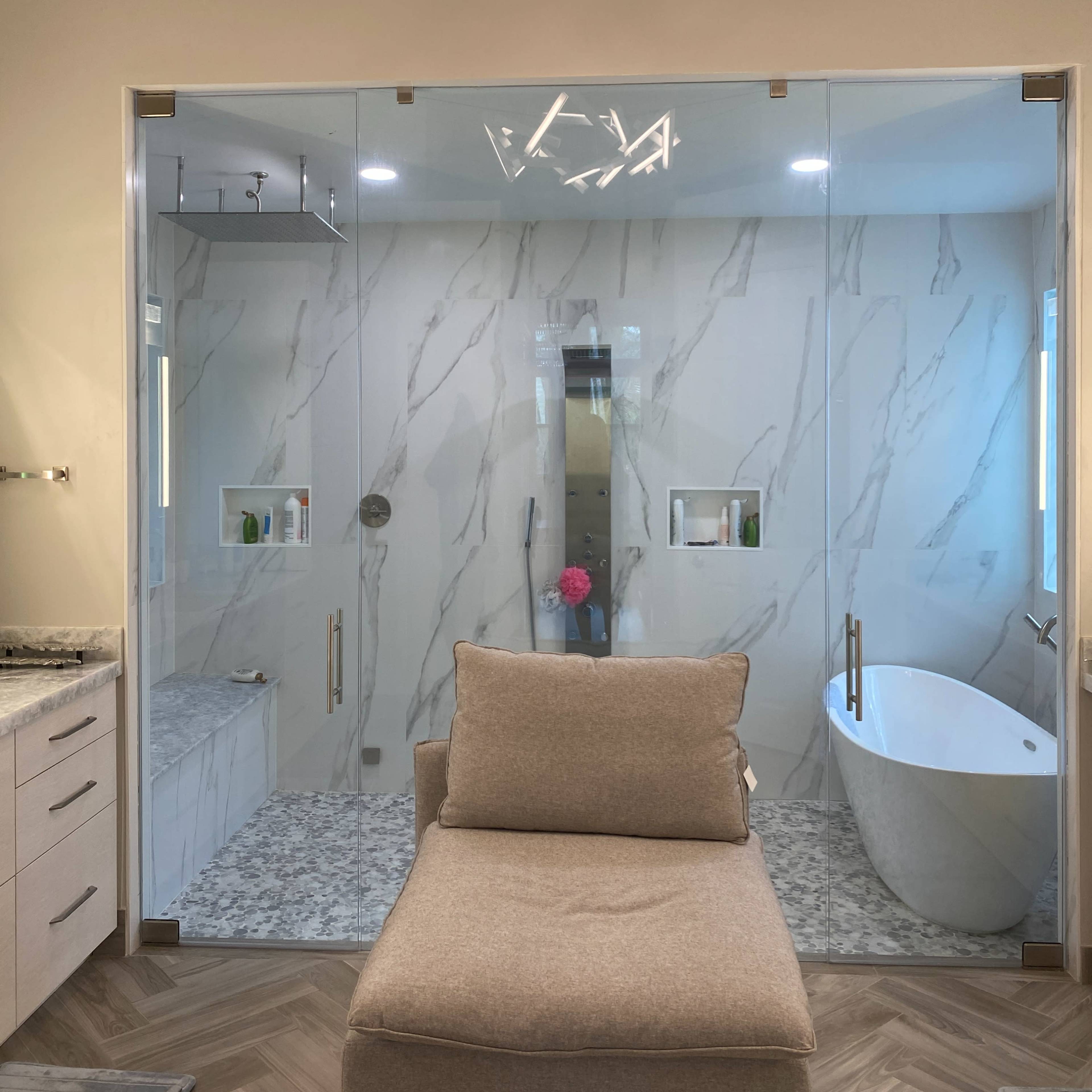A modern bathroom features a glass-enclosed shower, a freestanding bathtub, and a central seating area.