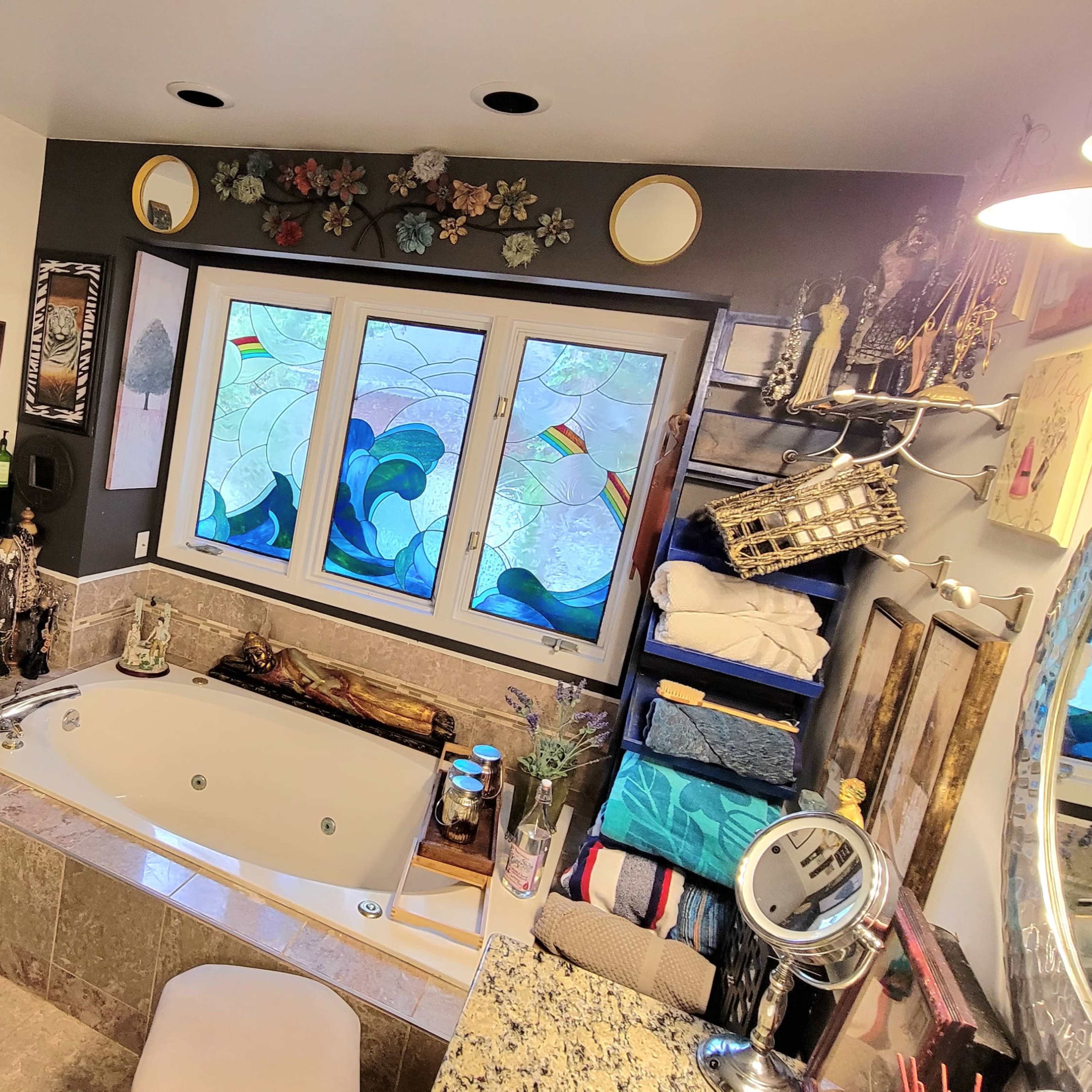 The bathroom features a corner tub, decorative wall art, and a variety of toiletries organized on shelves.