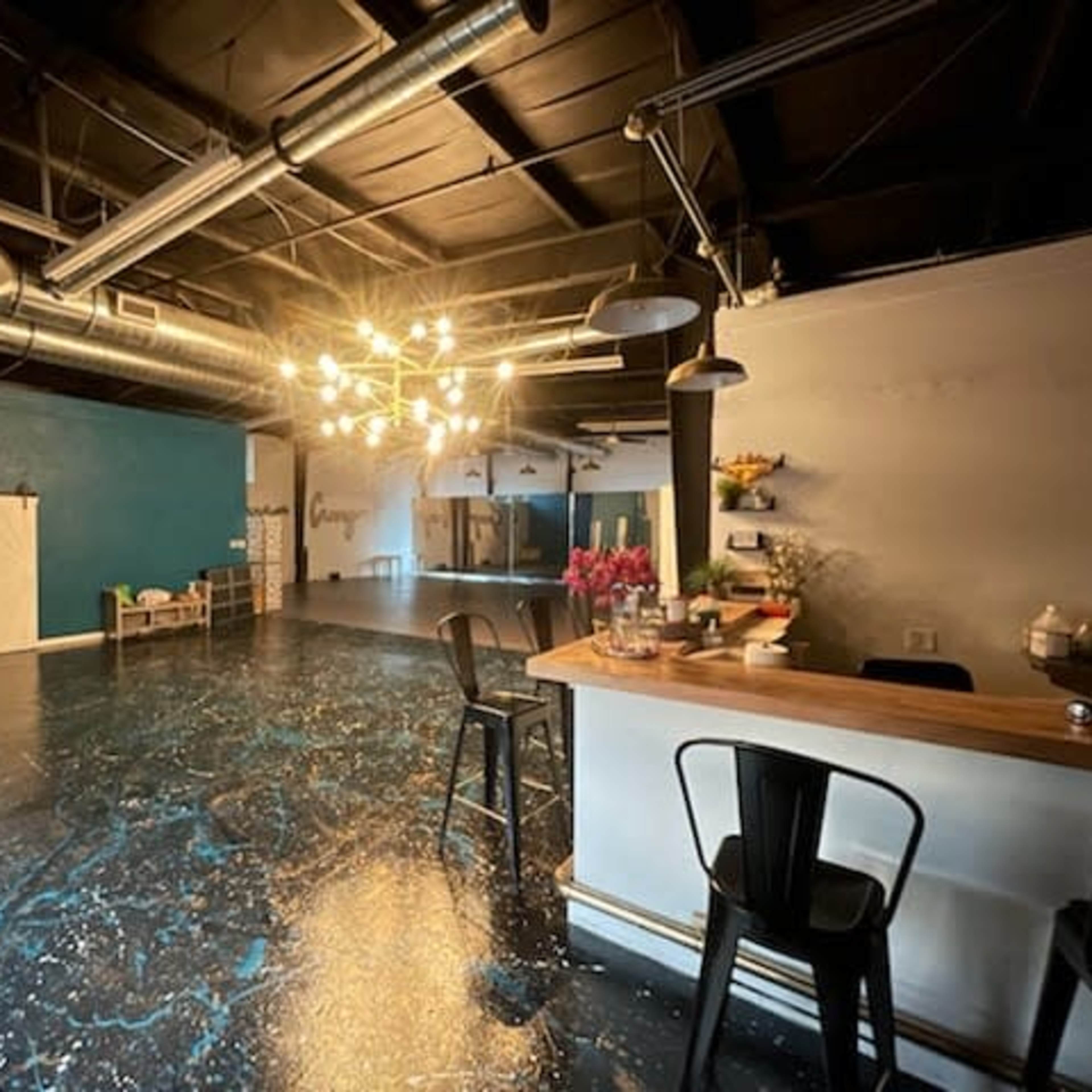 A spacious interior with a polished dark floor, a bar area with stools, and a blue accent wall.