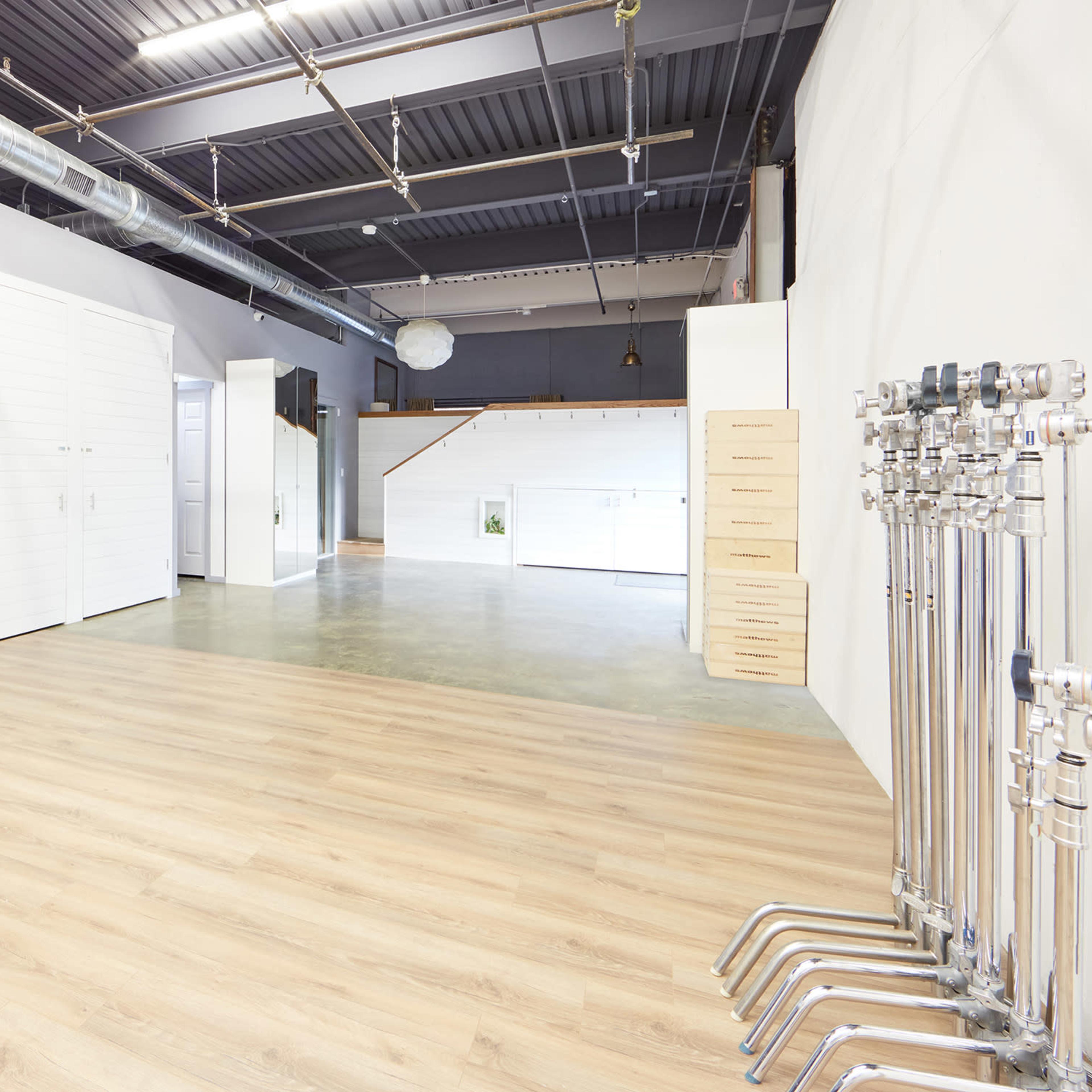 A spacious, modern interior with polished concrete floors, a kitchen area on the left, and a row of pipes along the right wall.