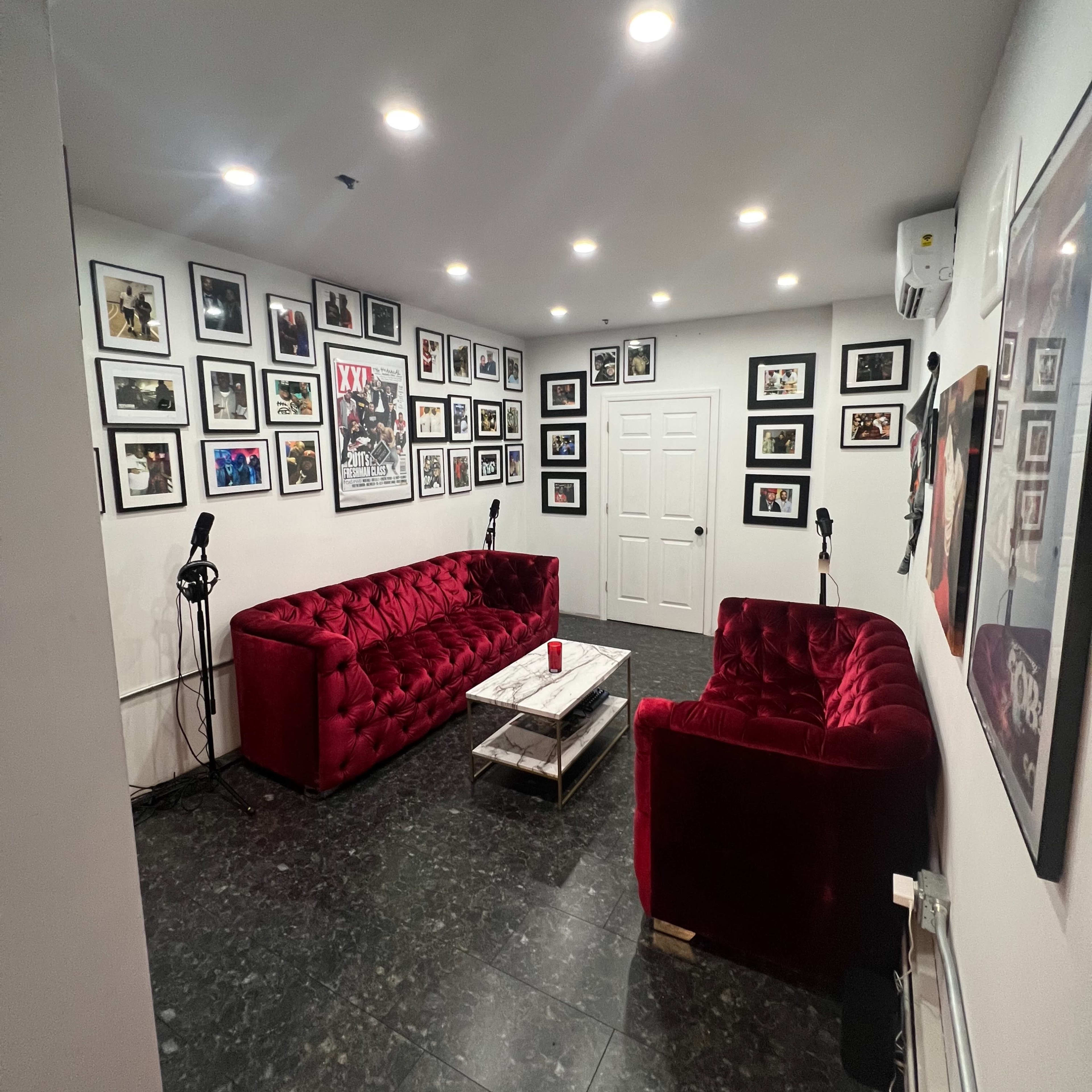 A small room with red tufted sofas, a coffee table, and walls covered in framed photographs.