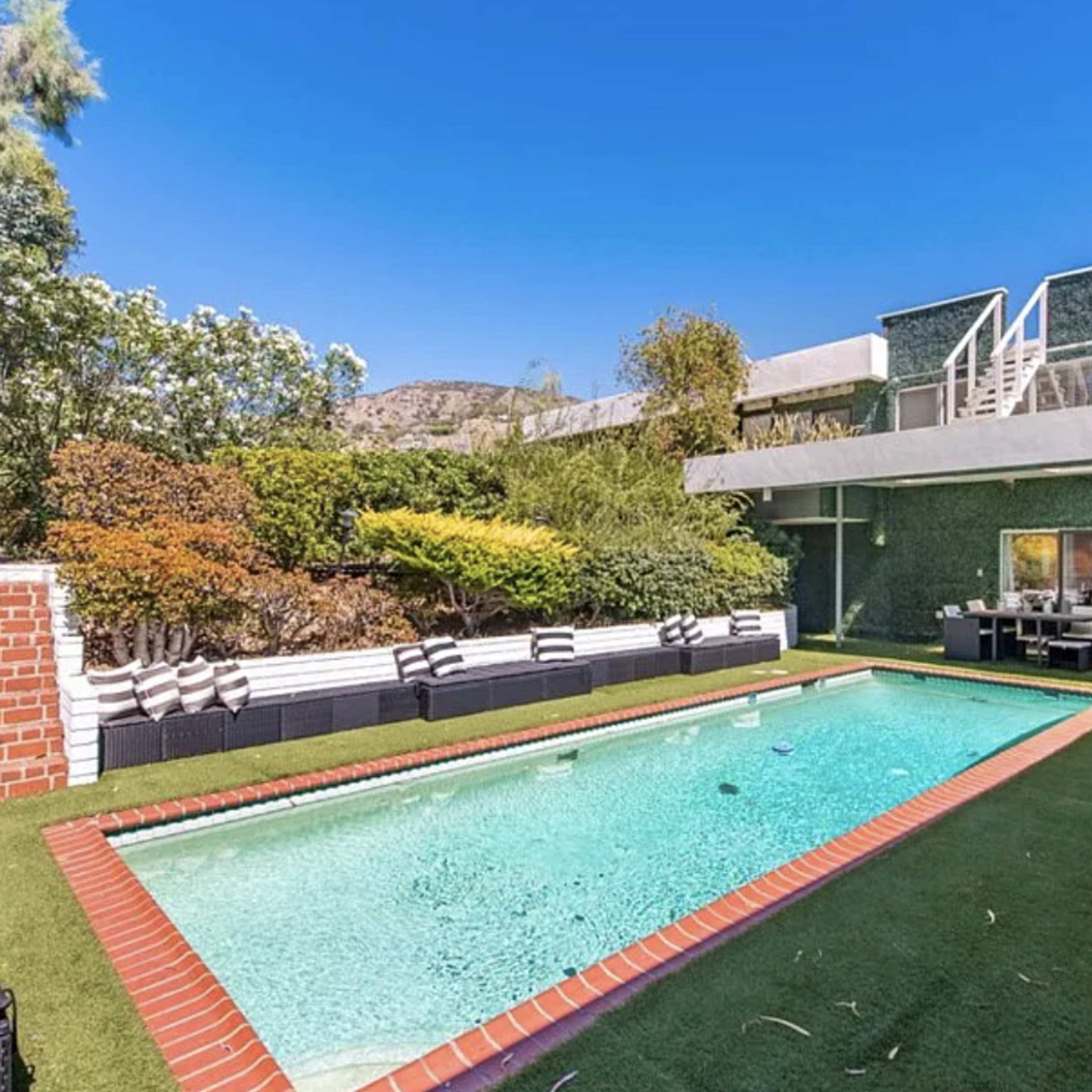 A modern house with a swimming pool surrounded by landscaped greenery and outdoor seating.