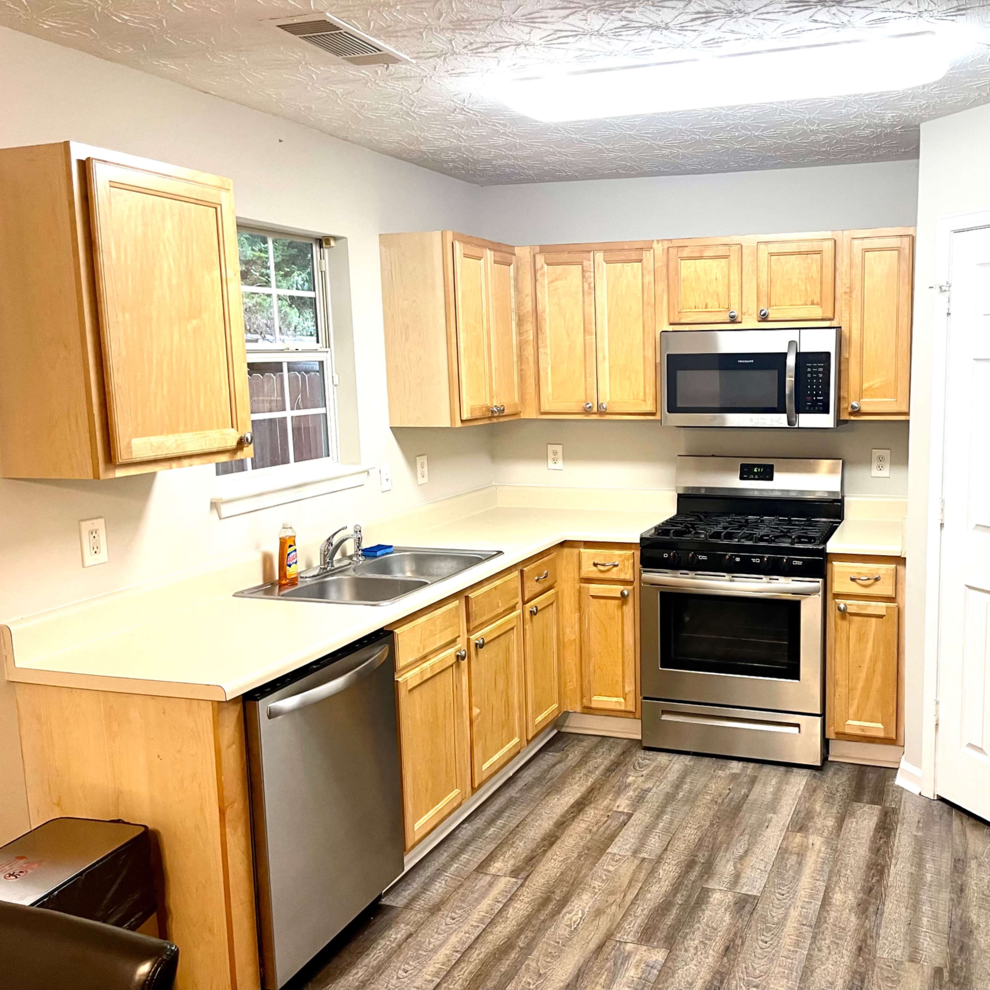 A kitchen with wooden cabinets, stainless steel appliances, and a light-colored countertop.