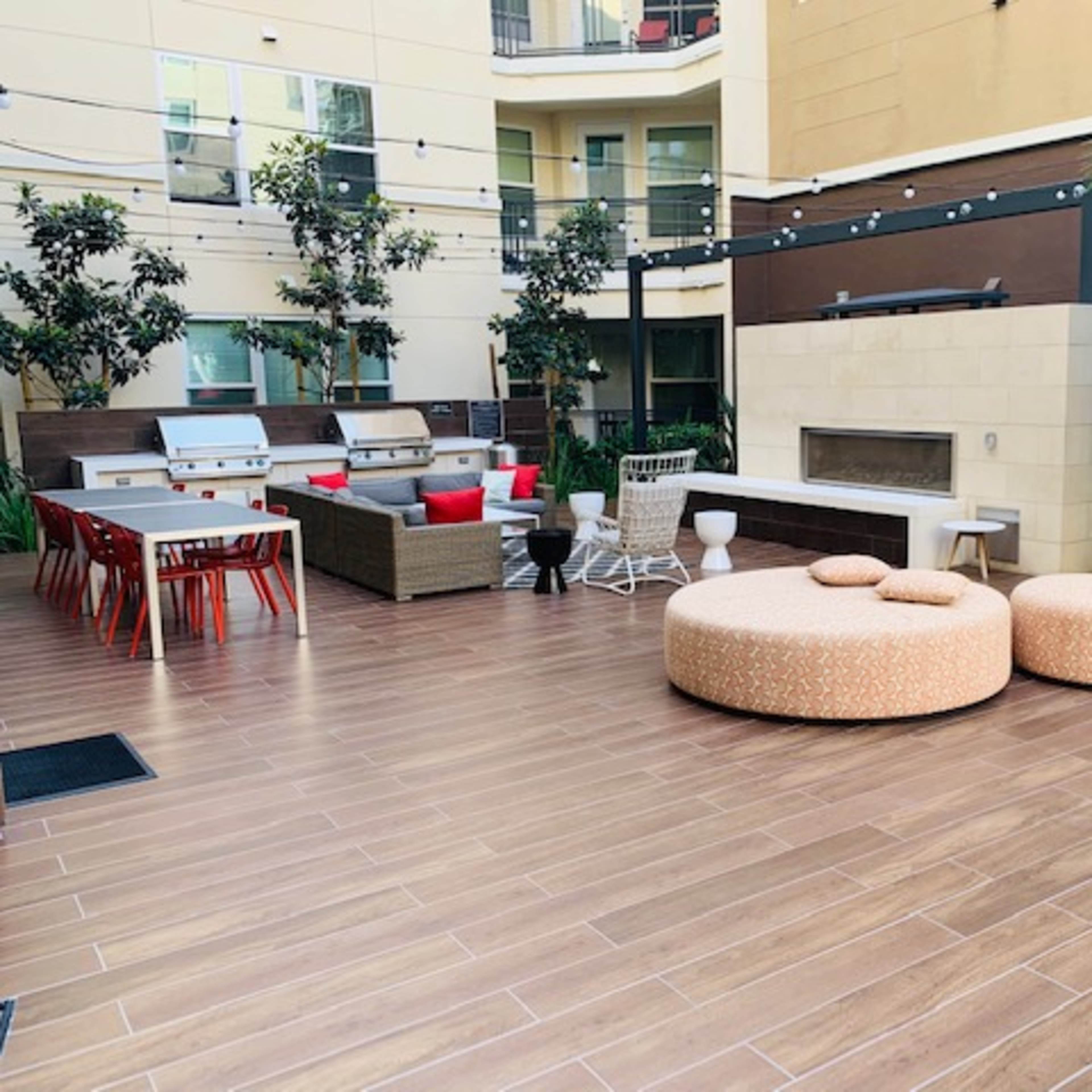 A modern outdoor lounge area featuring a patio with seating arrangements, including a fire pit and potted plants.