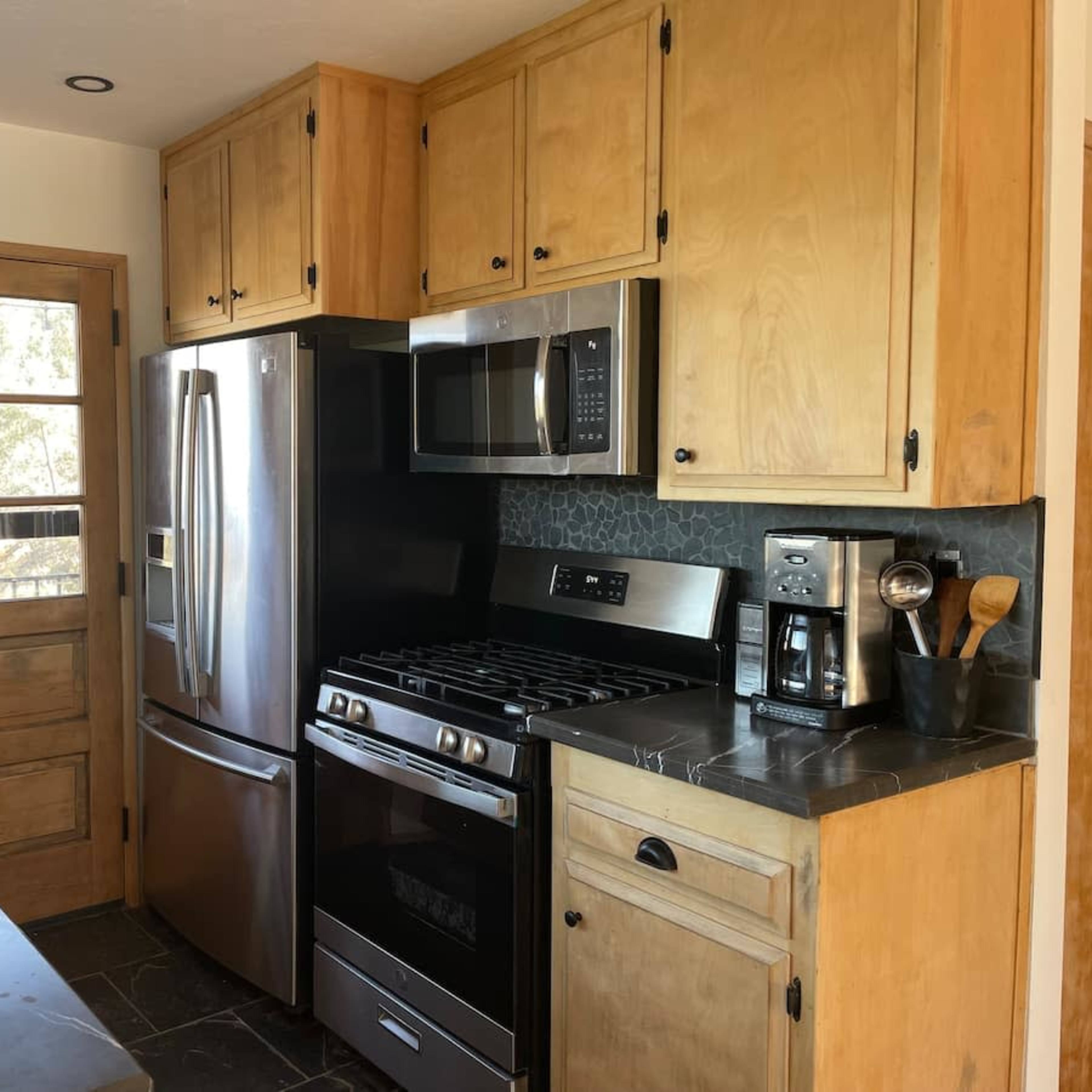 A kitchen with wooden cabinets, stainless steel appliances, and a door leading outside.